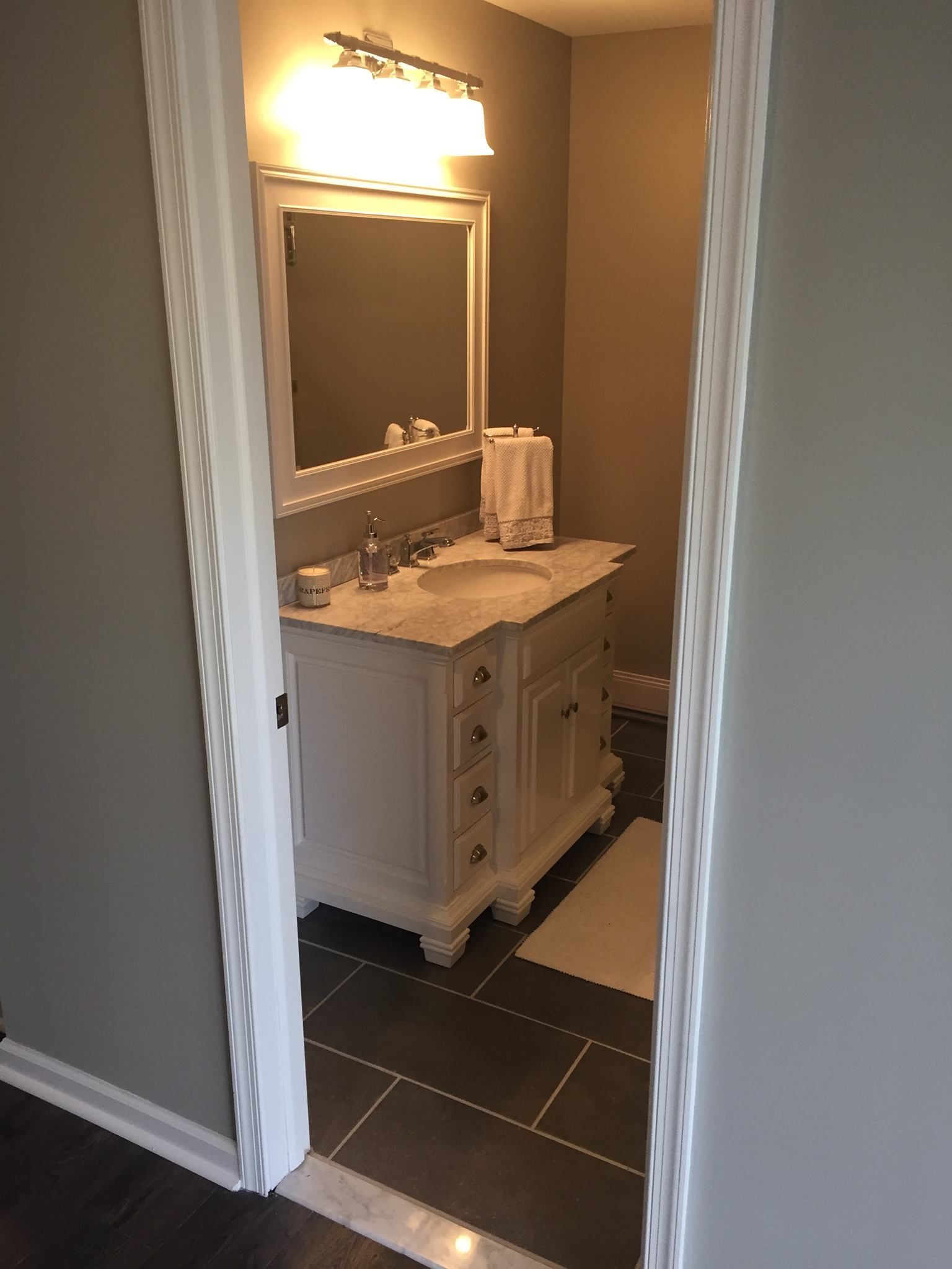 A bathroom with a white vanity and a mirror