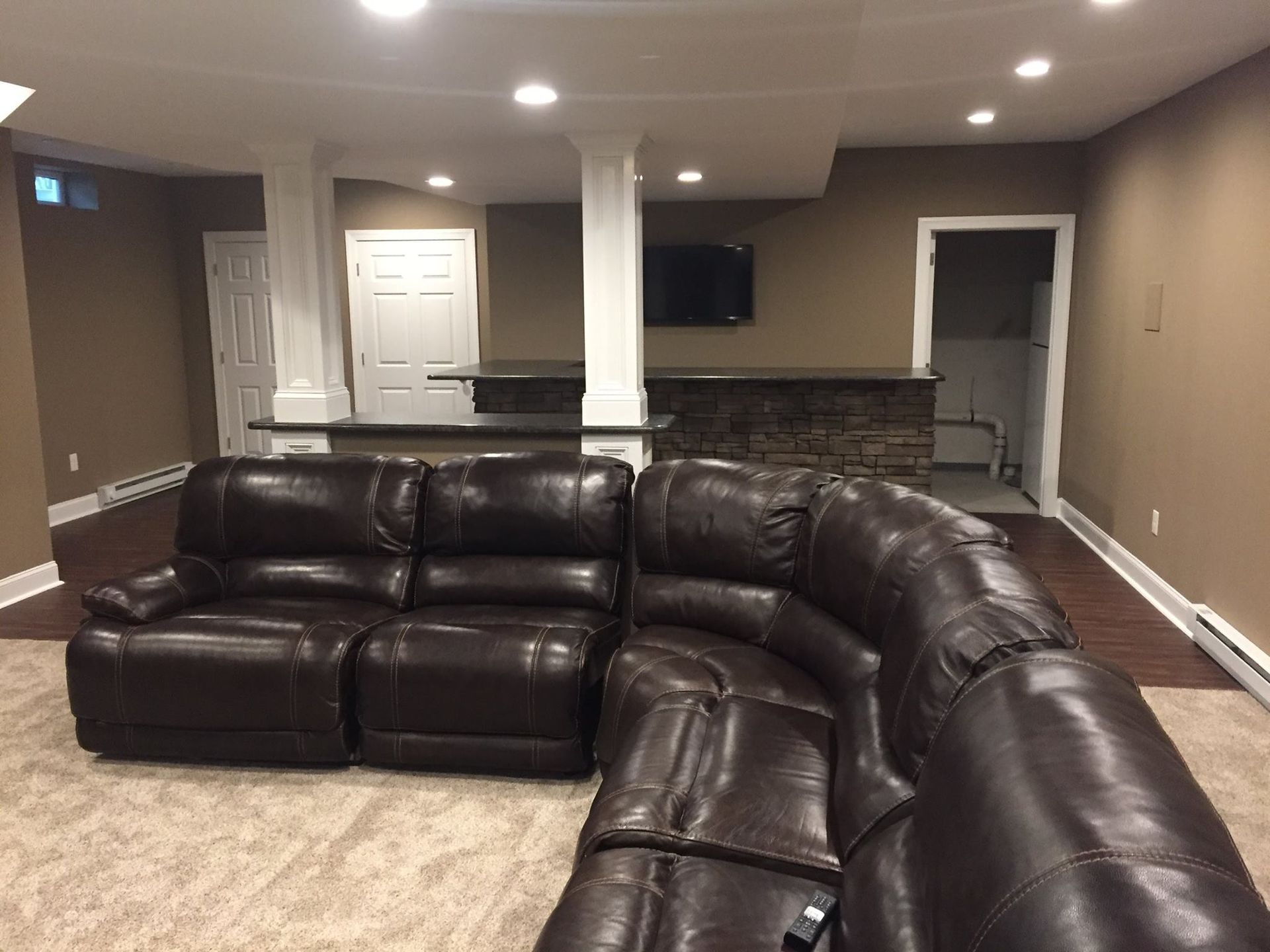 A living room with a brown leather sectional couch and a bar.