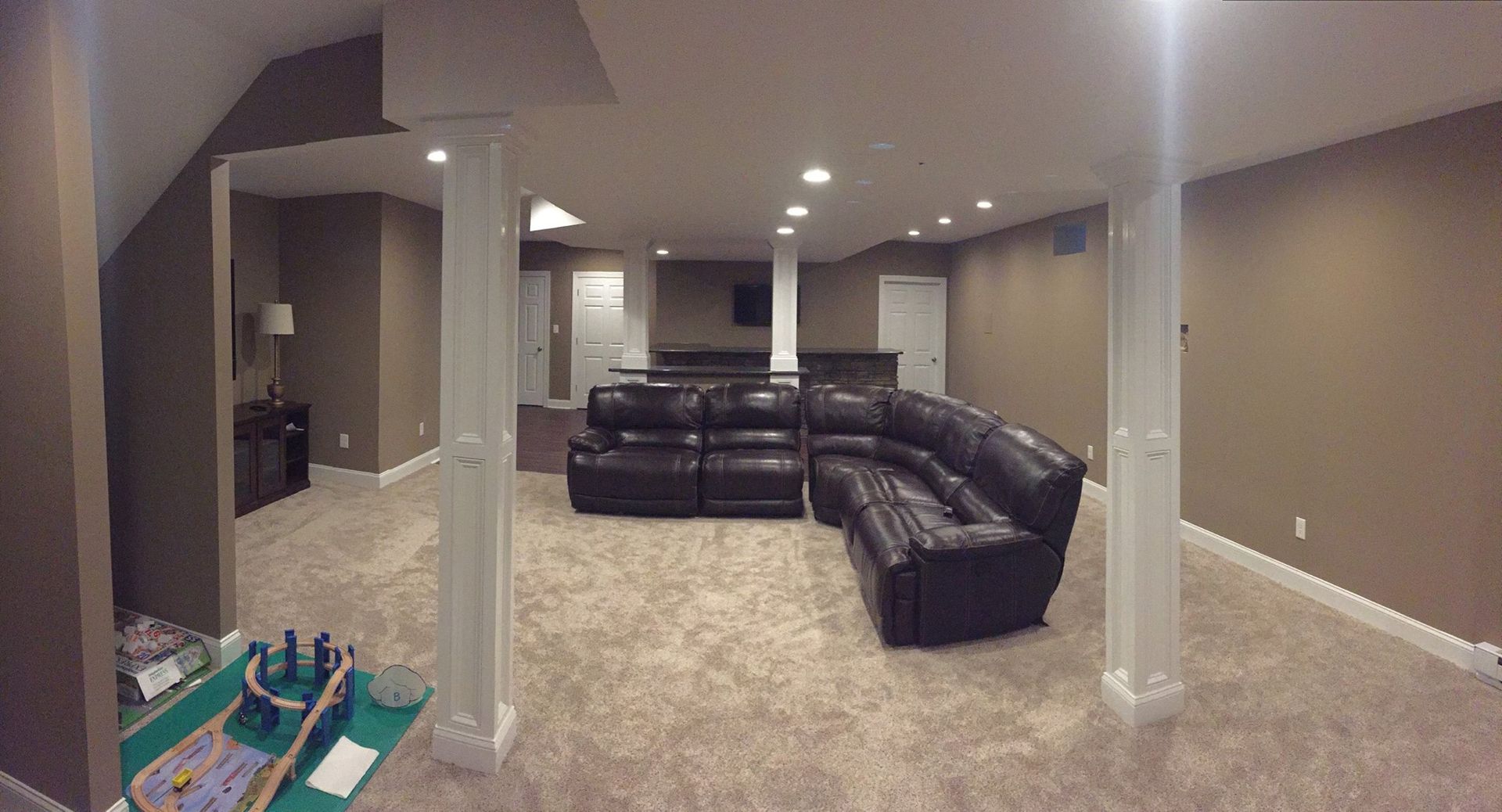 A living room in a basement with a couch and a table.