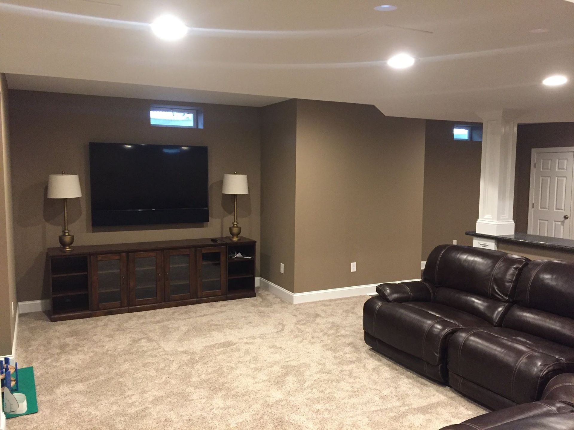 A living room in a basement with a couch and a flat screen tv.