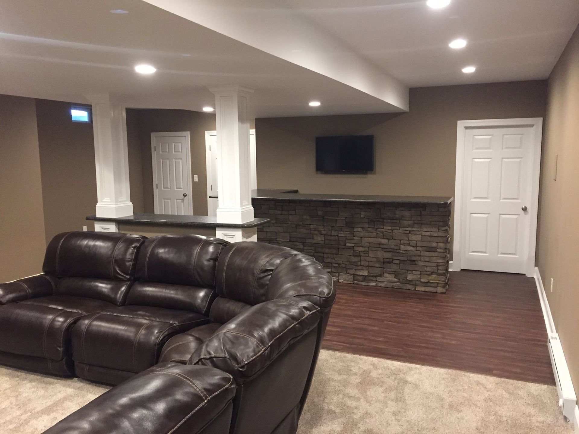 A living room with a brown leather couch and a stone bar.