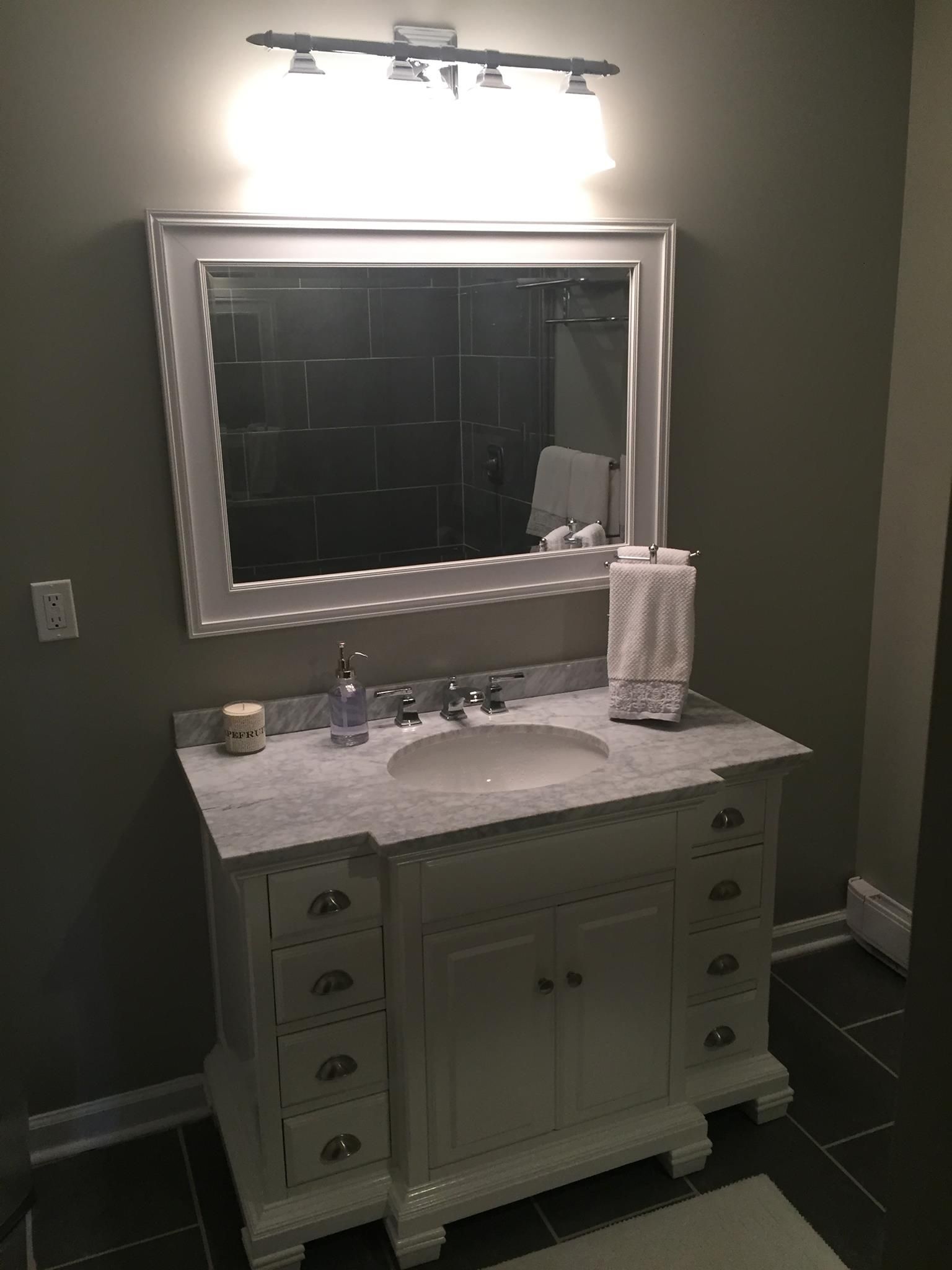 A bathroom with a sink , mirror and light fixture