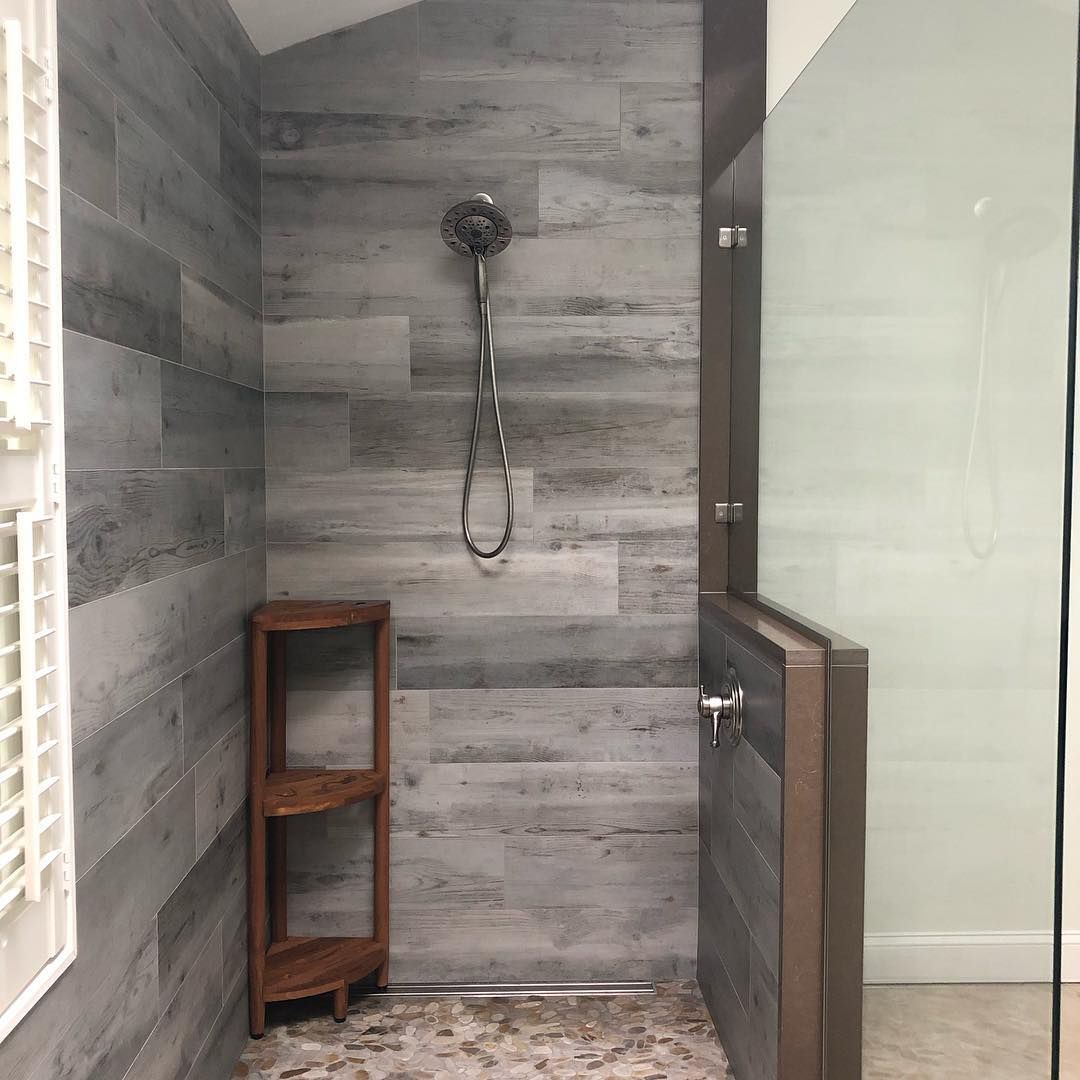 A bathroom with a walk in shower and a wooden shelf.