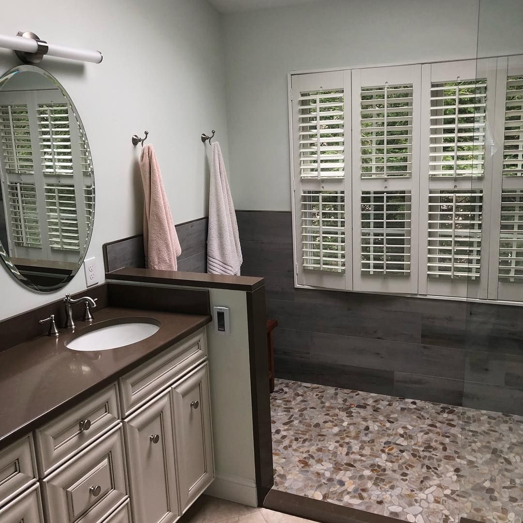 A bathroom with a sink , mirror , and walk in shower.
