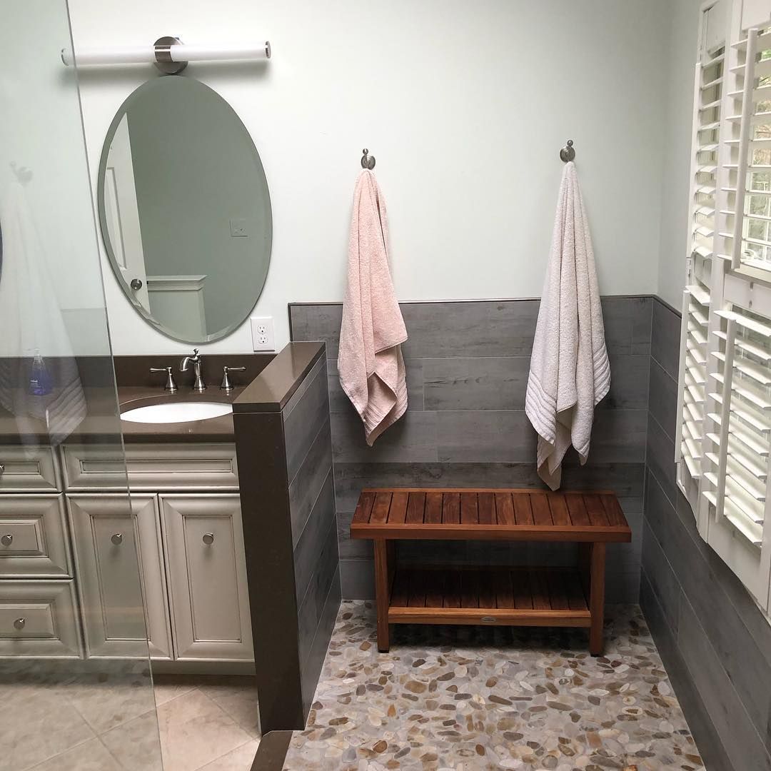 A bathroom with a sink a mirror and a wooden bench