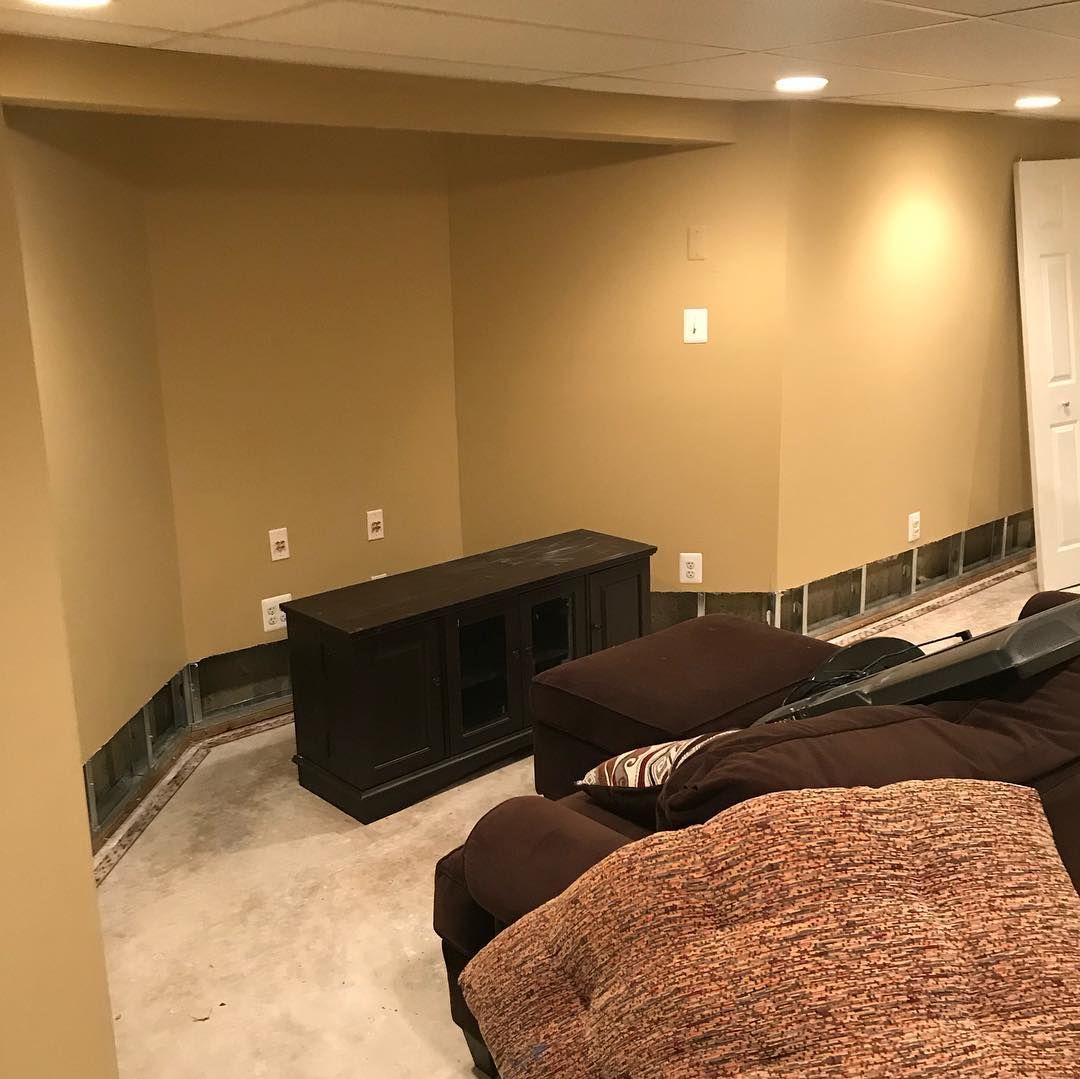 A living room with a couch , ottoman , and entertainment center.