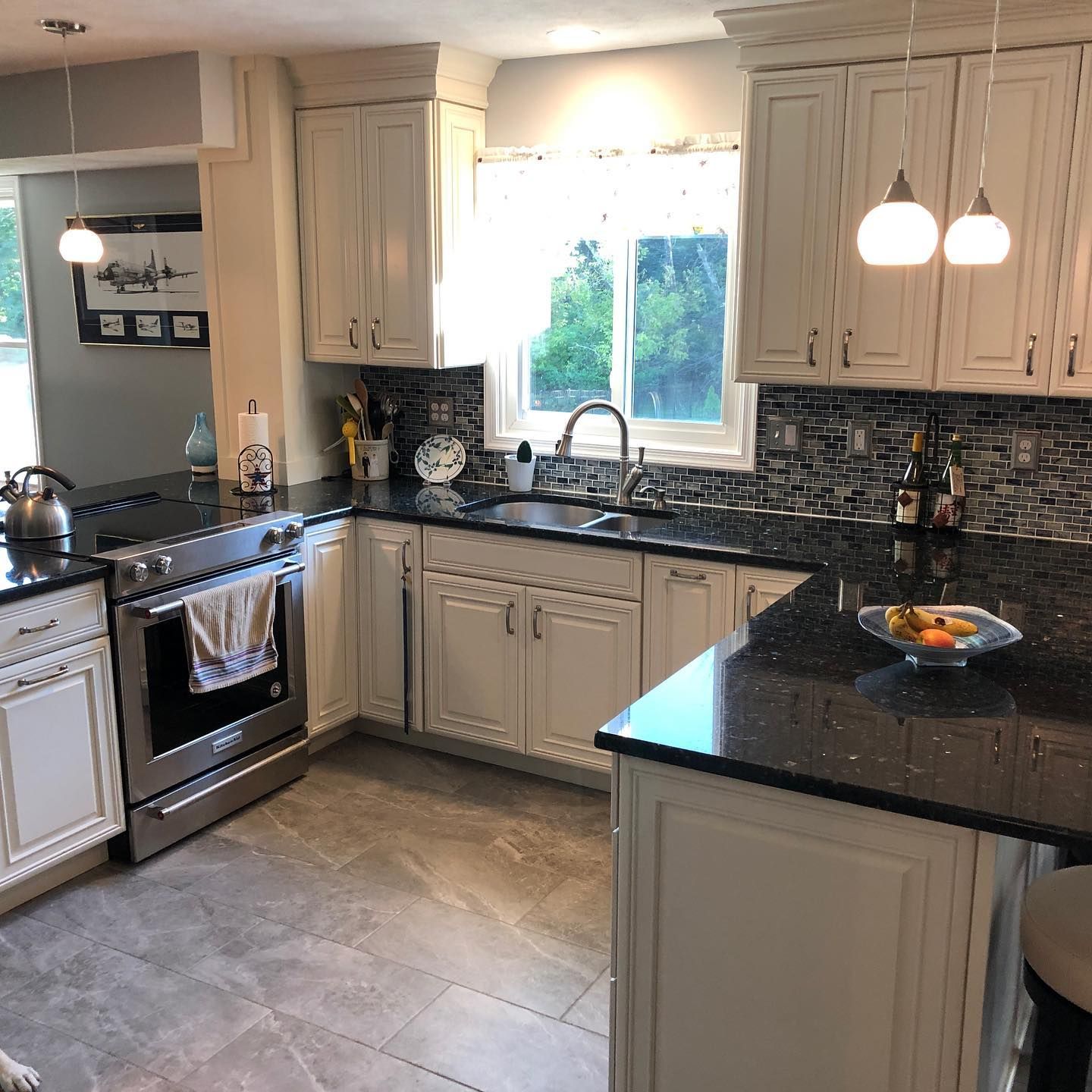 A kitchen with white cabinets and black counter tops