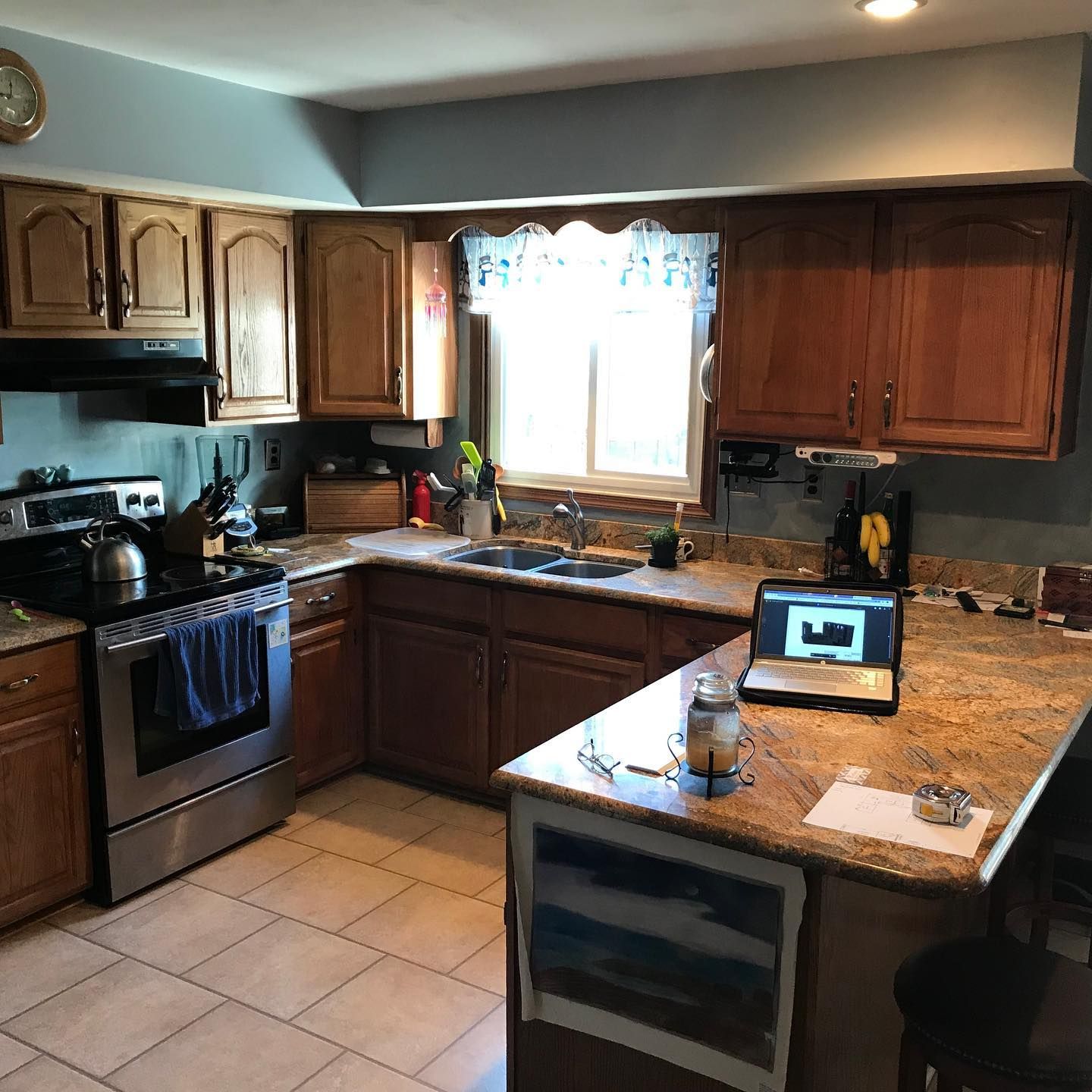 A kitchen with wooden cabinets and a laptop on the counter