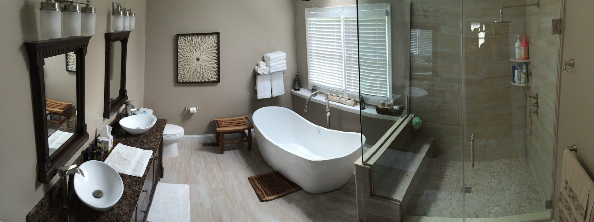A bathroom with a tub , sinks , mirrors and a walk in shower.