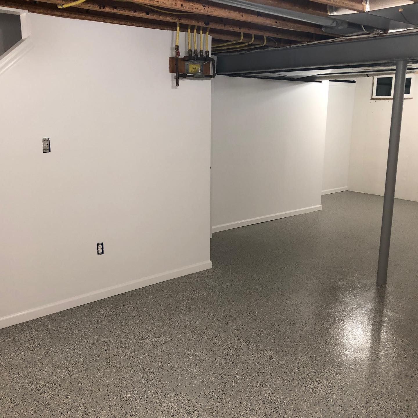 An empty basement with a concrete floor and white walls.