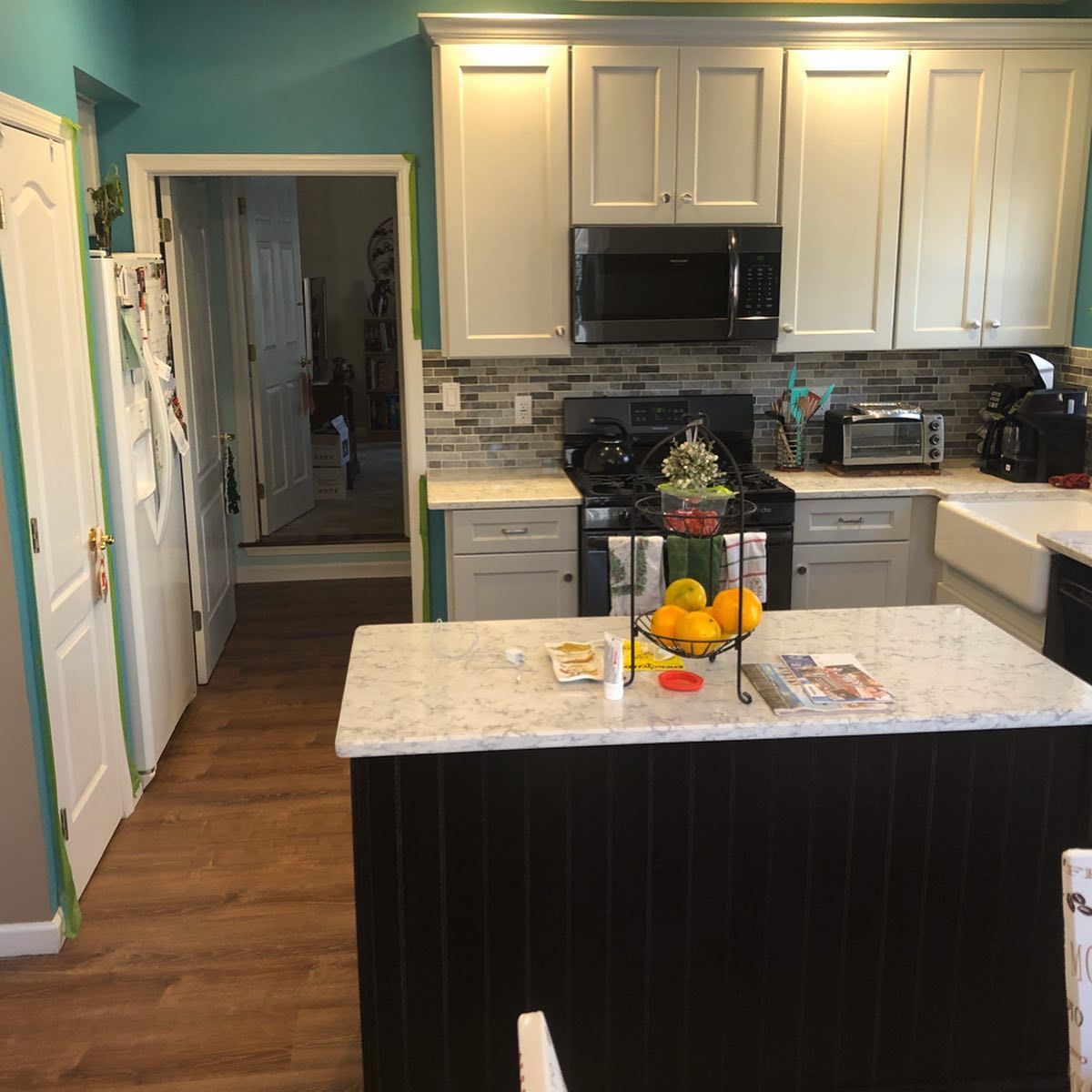 A kitchen with white cabinets and a black island