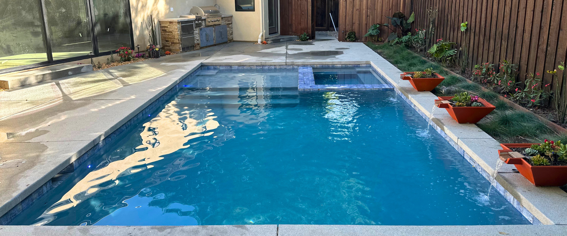 Swimming pool with white deck and furniture in an outdoor setting.