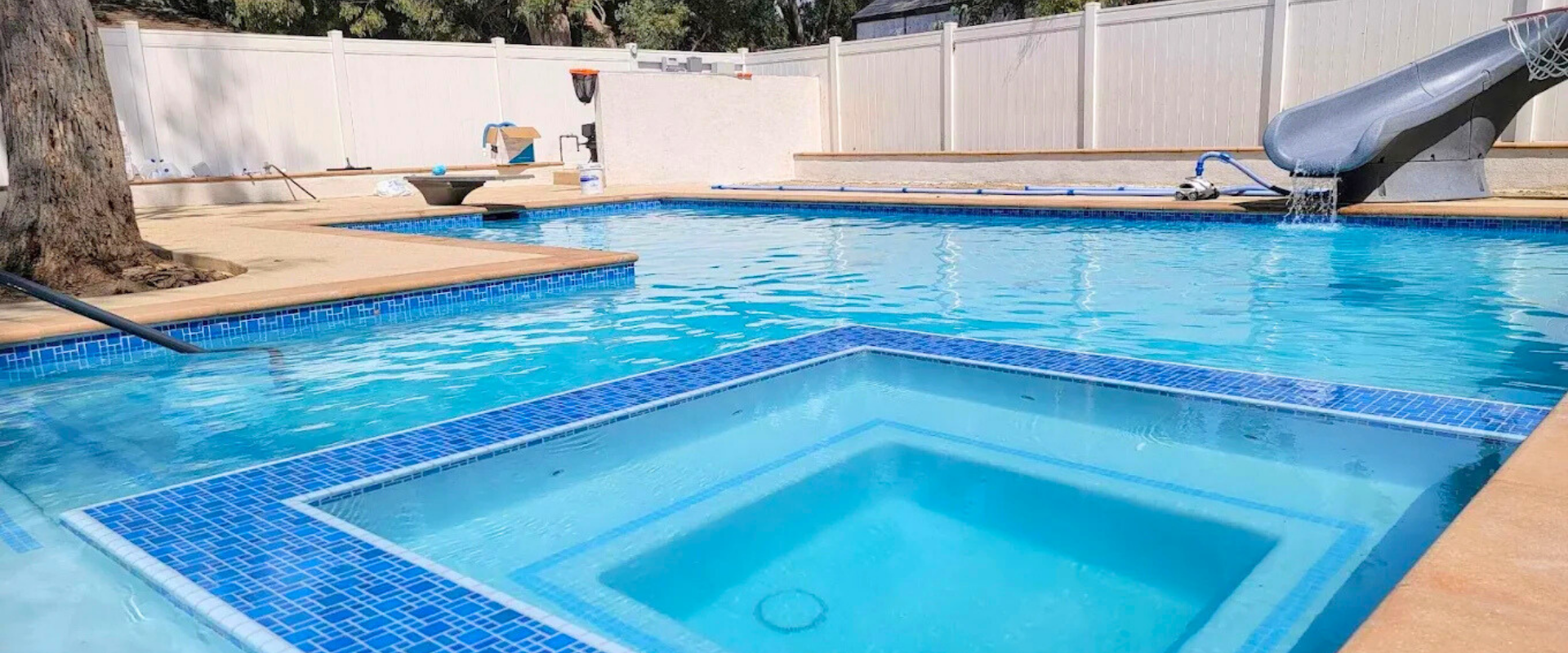 Swimming pool with white deck and furniture in an outdoor setting.