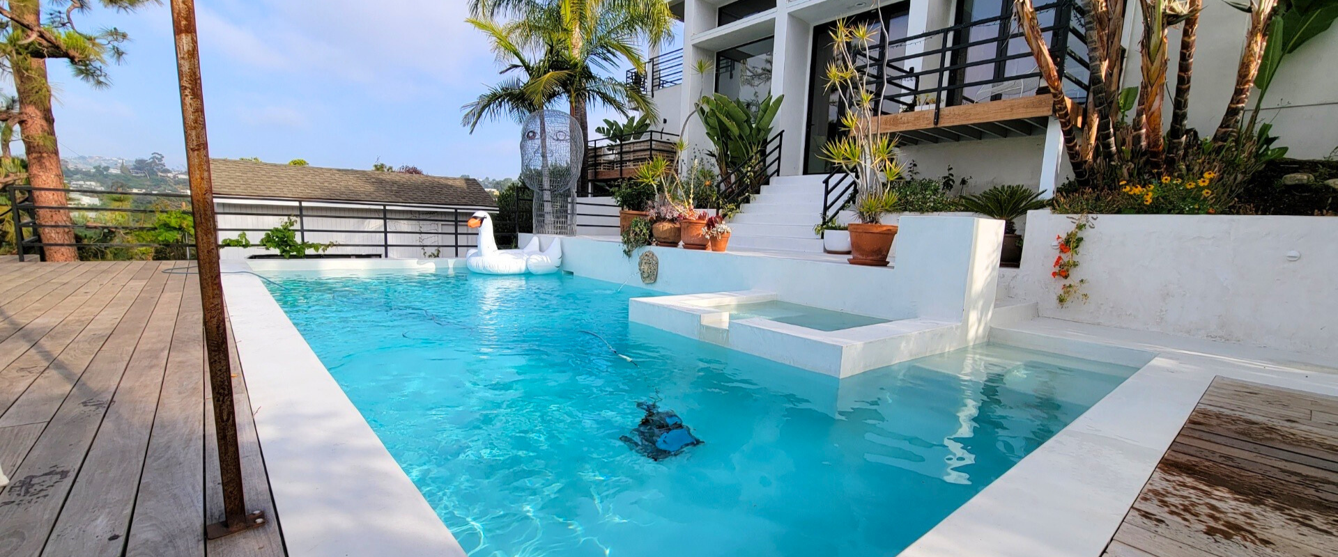 A swimming pool in a tropical setting with white walls and a white building. Turquoise water.