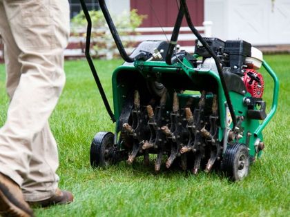 A green lawn aerator is sitting on top of a lush green lawn. A green lawn aerator is sitting on top of a lush green lawn.