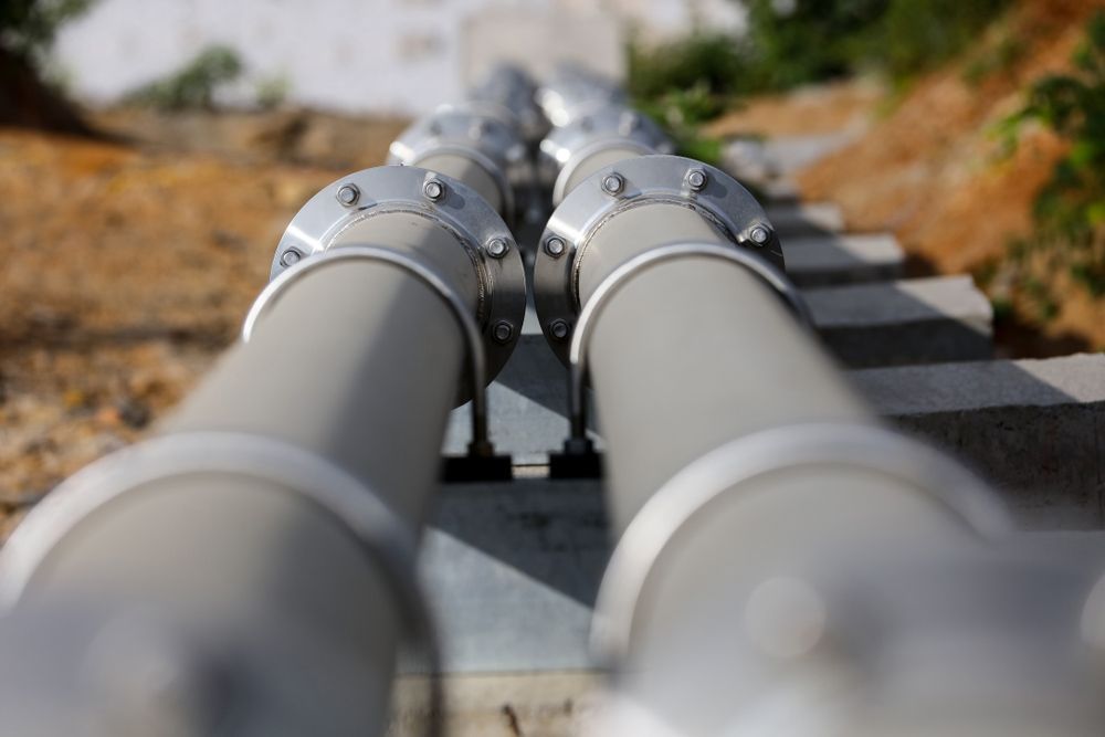 A Row Of Gray Pipes Are Lined Up On A Concrete Surface — NSL Plumbing and Gas in Terranora, NSW