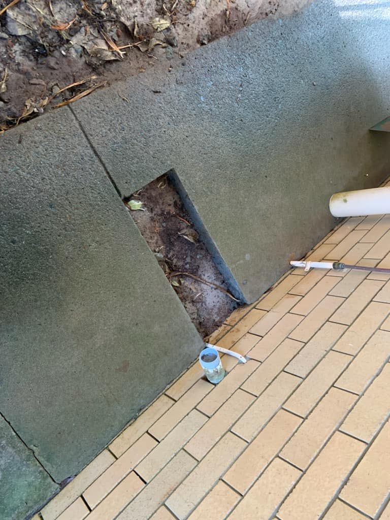 A Close Up Of A Brick Floor With A Hole In It — NSL Plumbing and Gas in Banora Point, NSW