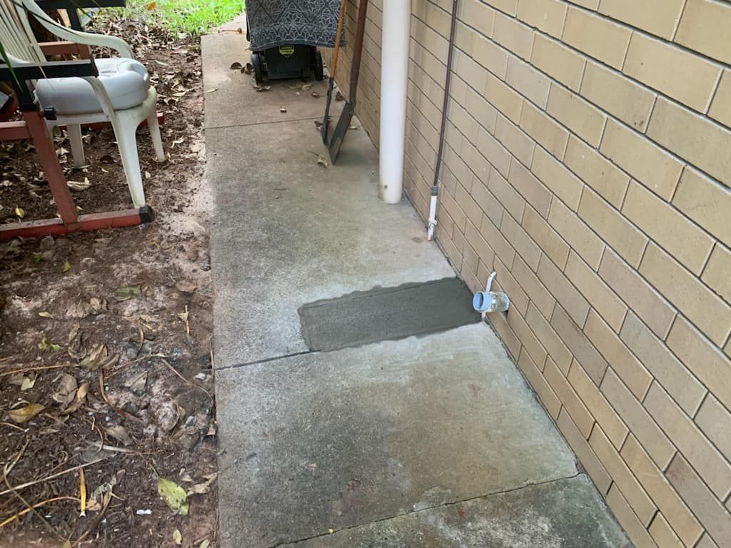 A Sidewalk Next To A Brick Wall With A Chair In The Background — NSL Plumbing and Gas in Banora Point, NSW
