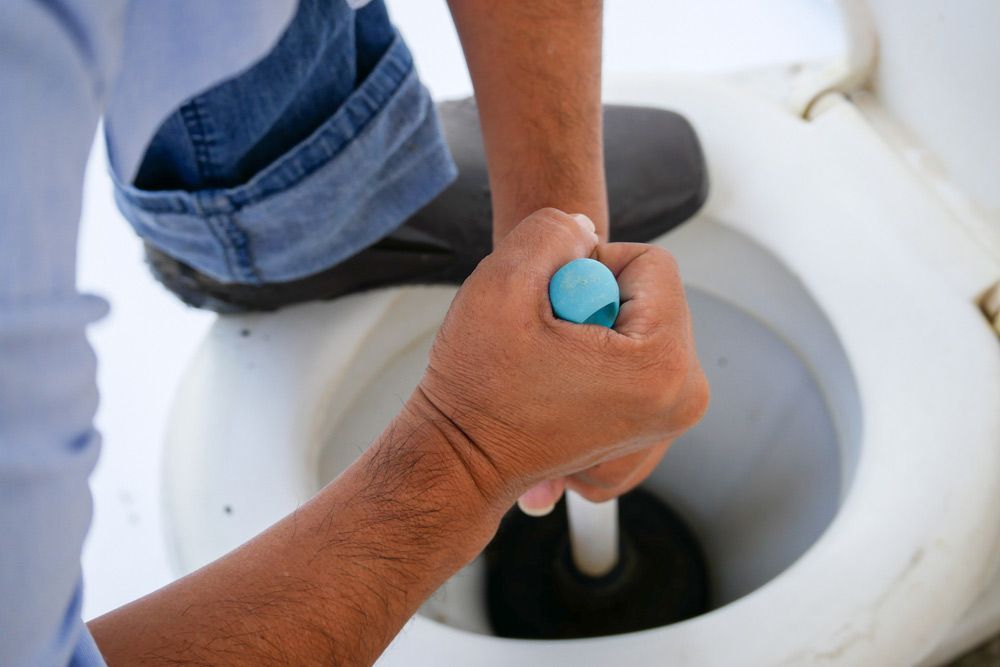 A Man Is Using A Plunger To Unblock A Toilet — NSL Plumbing and Gas in Banora Point, NSW