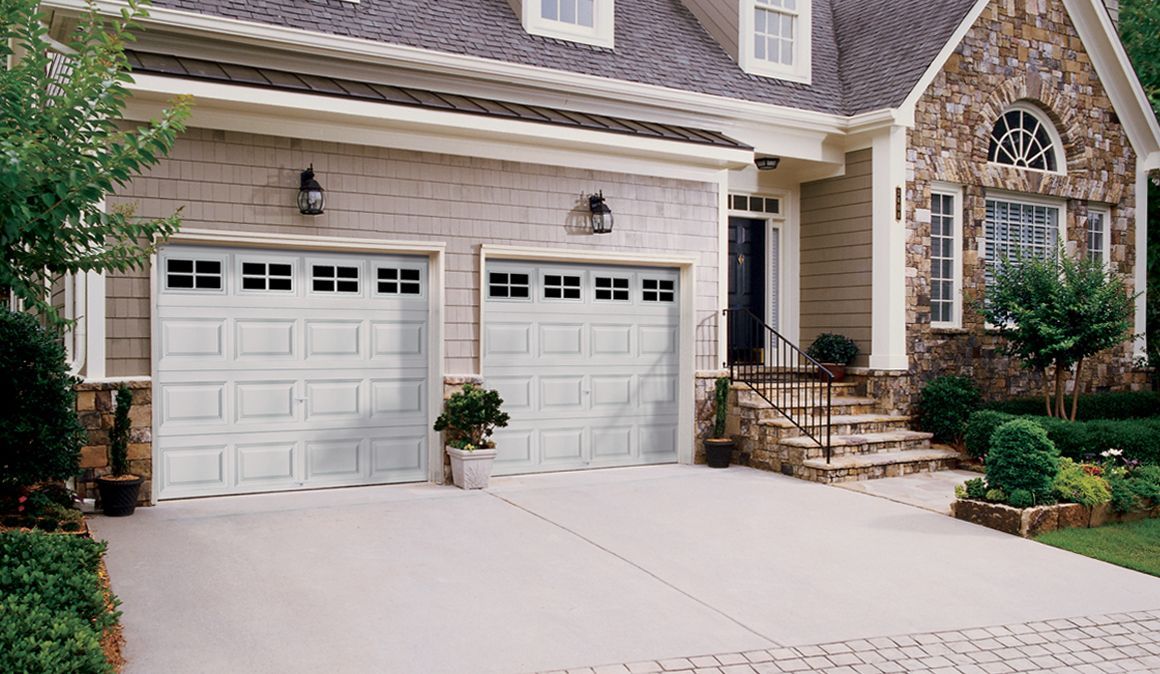 A large house with three white garage doors and a driveway.