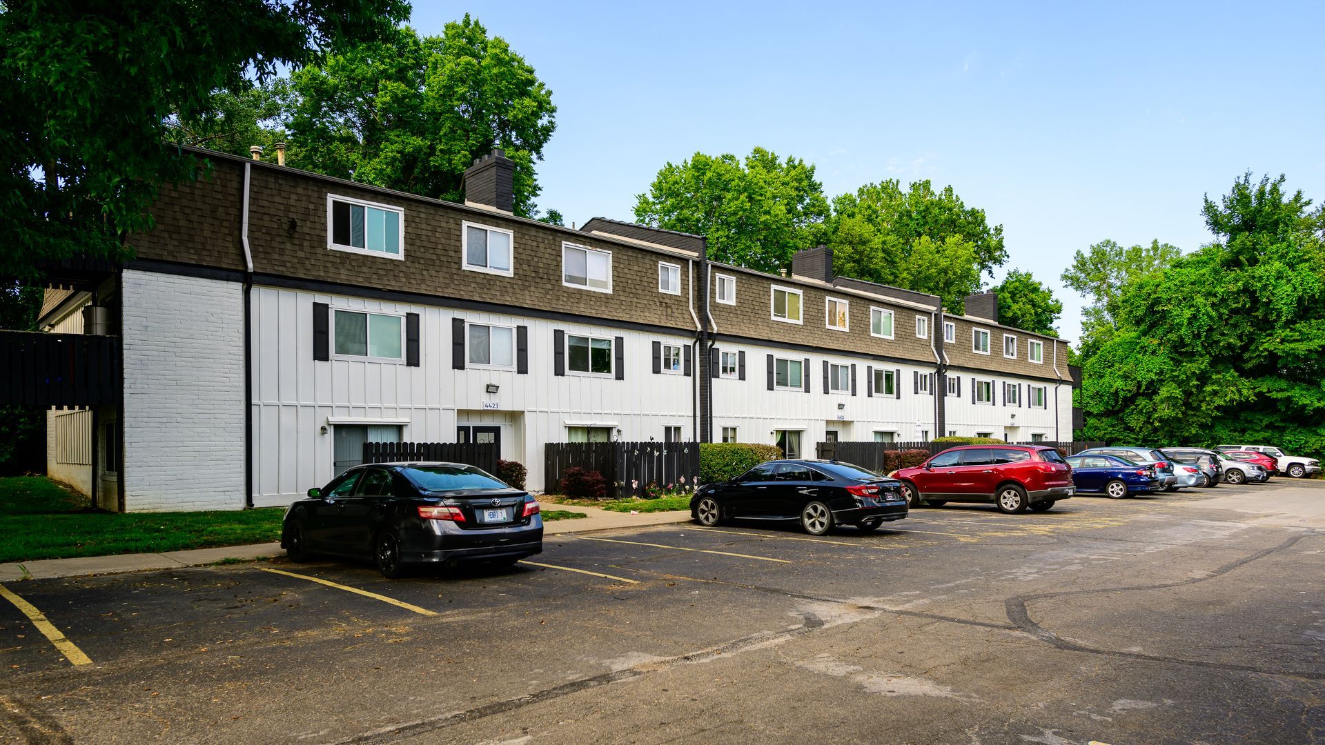 A row of cars are parked in front of a building.