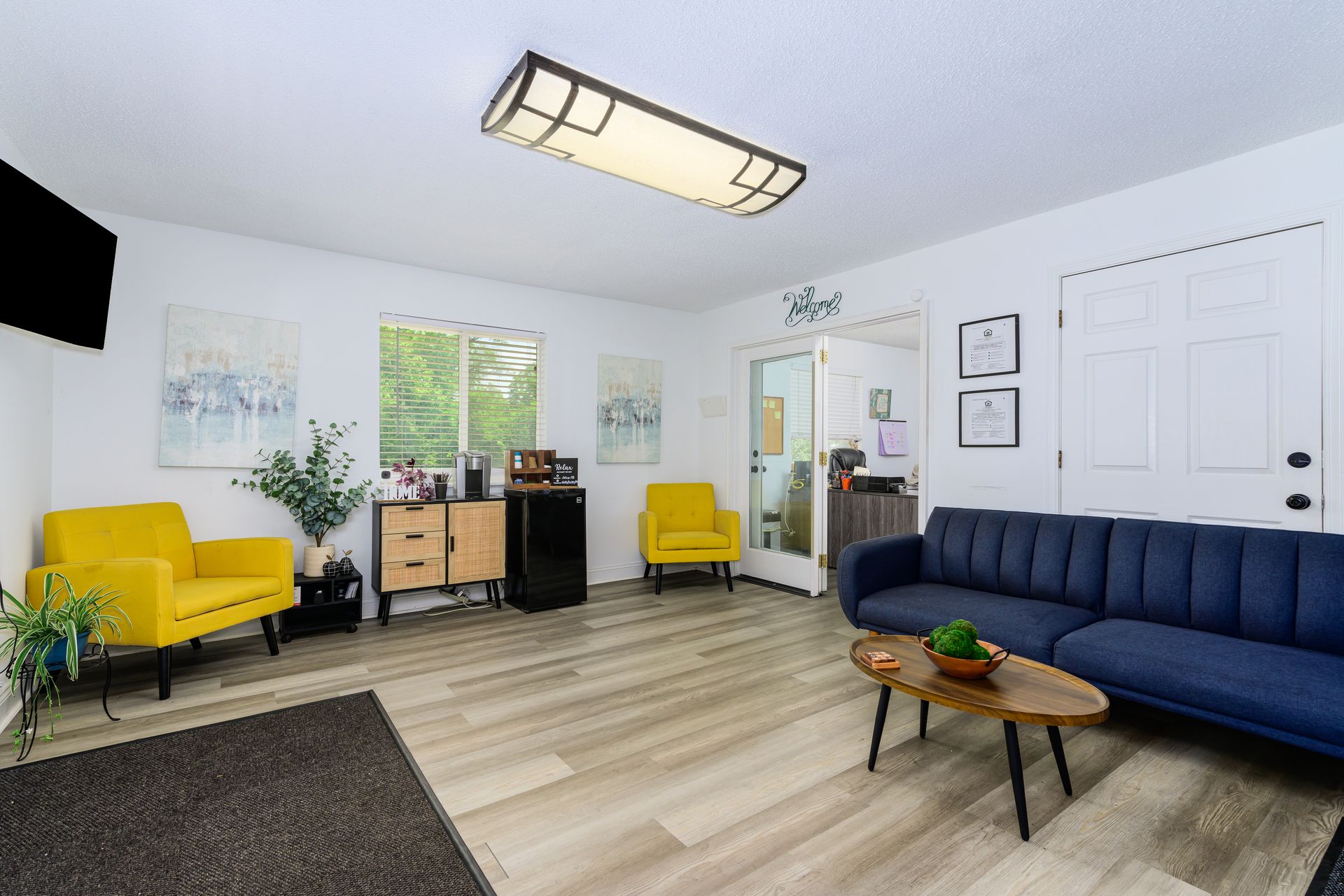 A living room with a blue couch , yellow chairs , and a coffee table.