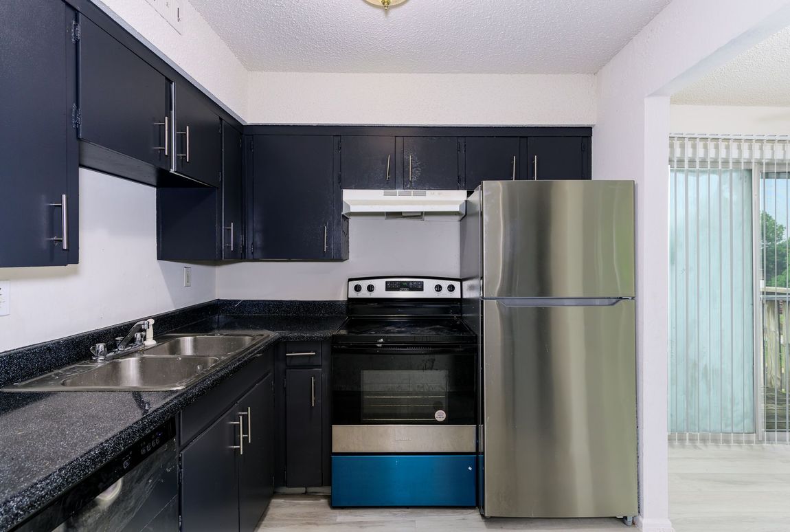 A kitchen with stainless steel appliances and black cabinets.