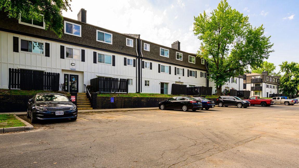 A parking lot in front of a building with cars parked in front of it.