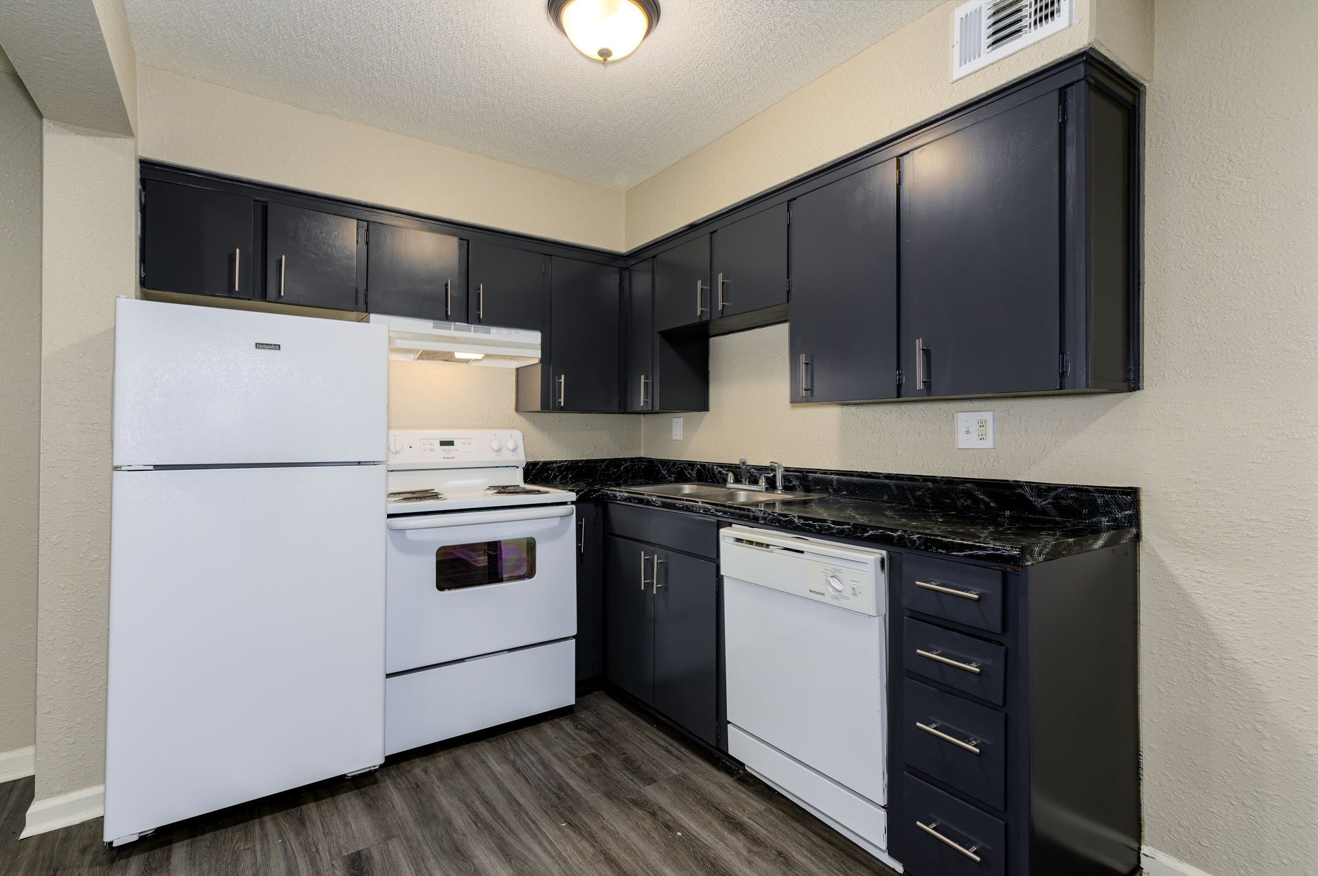 A kitchen with black cabinets and white appliances.