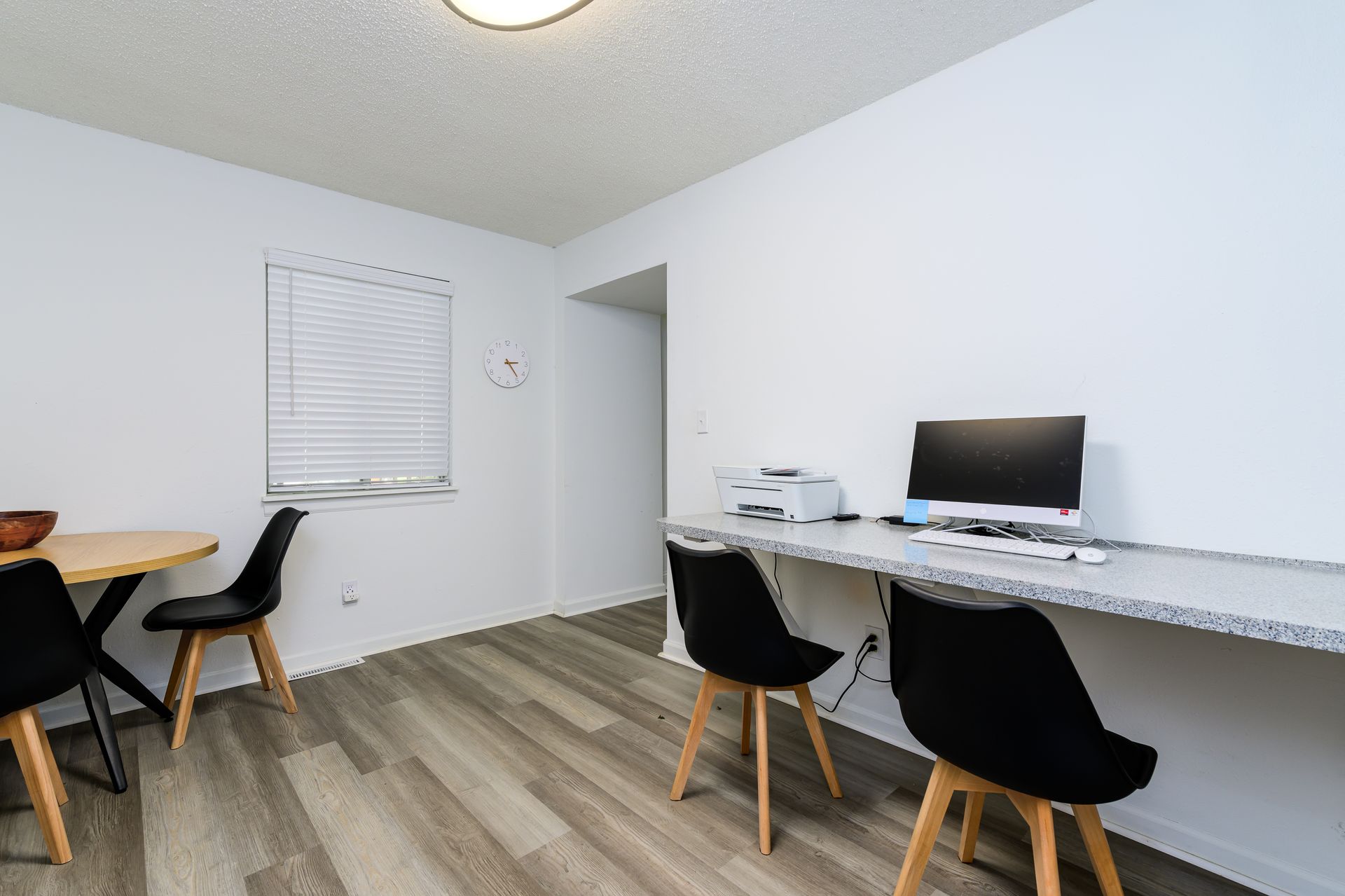A room with a desk and chairs and a computer on it