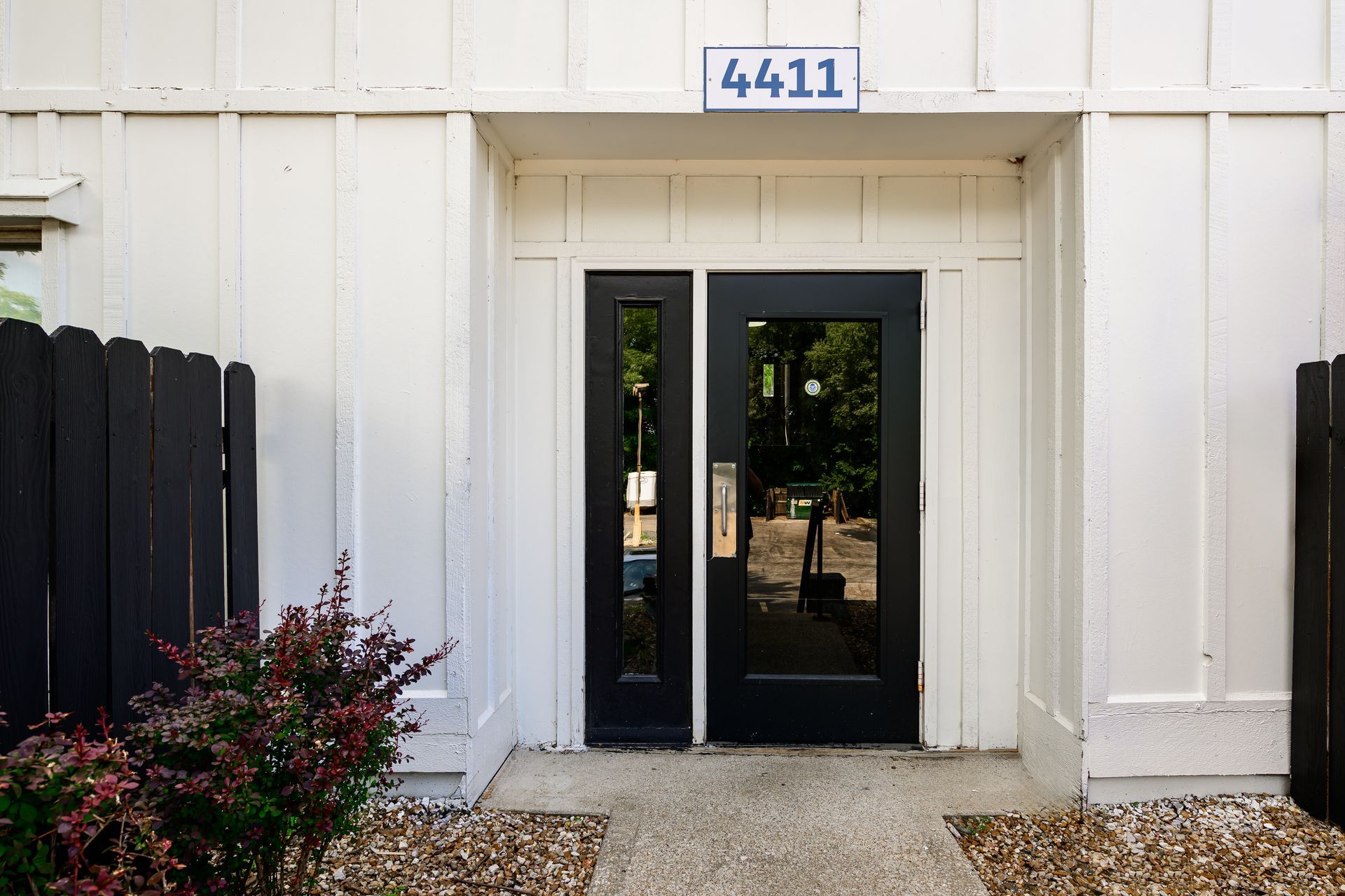 A white building with a black door and a sign that says 4411