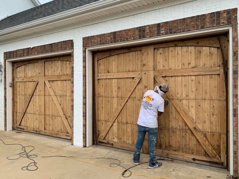 alex's painting & remodeling team staining a garage door