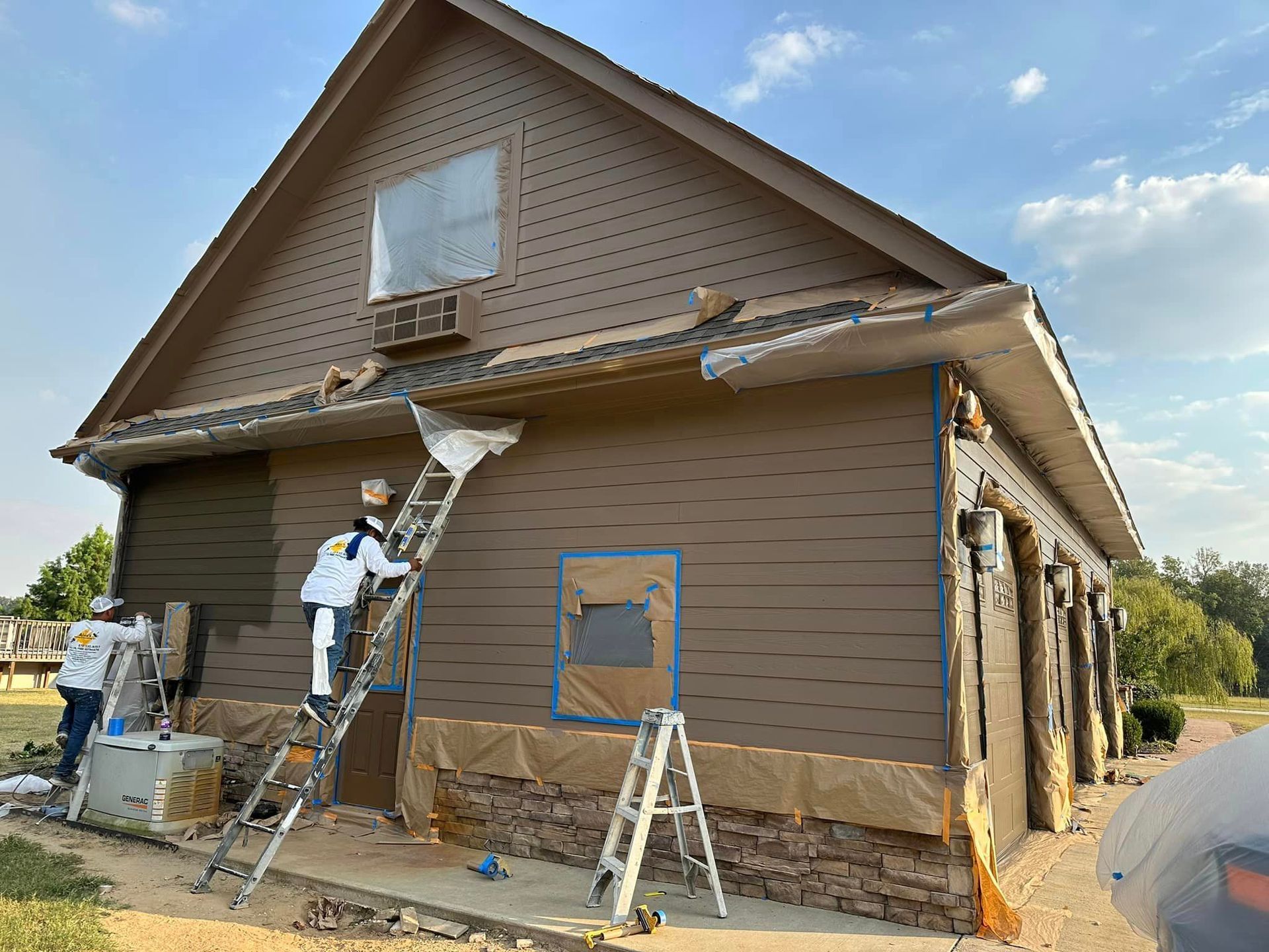 A group of people are painting a house with a ladder.