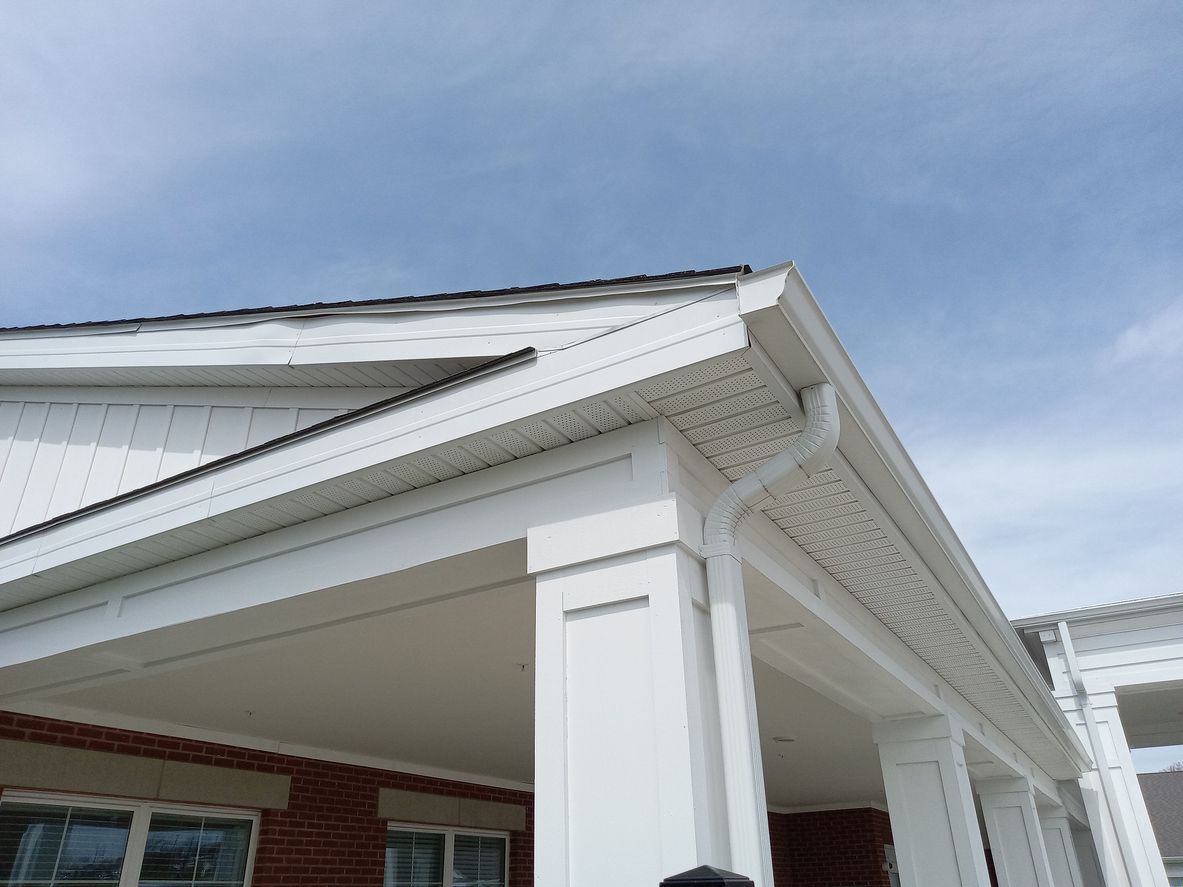 White house exterior with porch, gutters, and a blue sky.