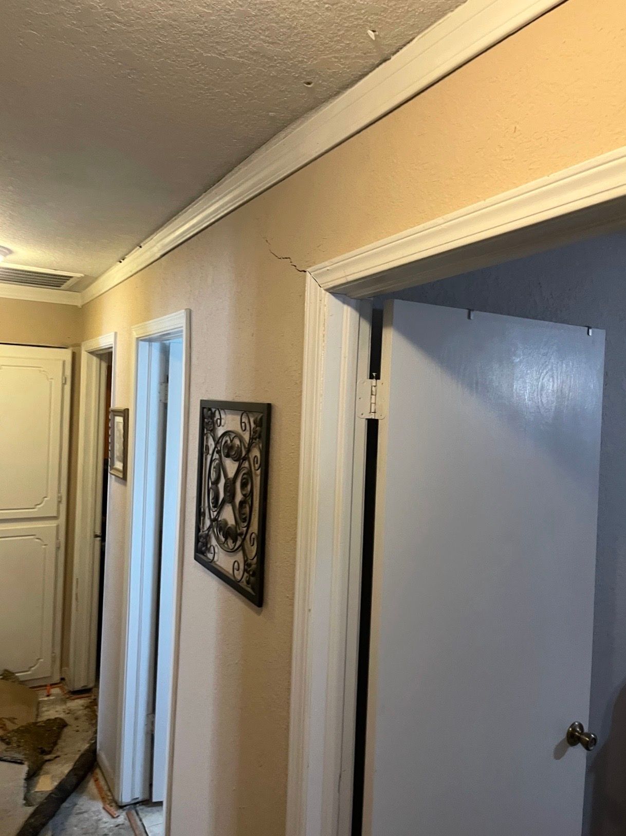 Narrow beige hallway with white trim, open doorways, and framed wall art.