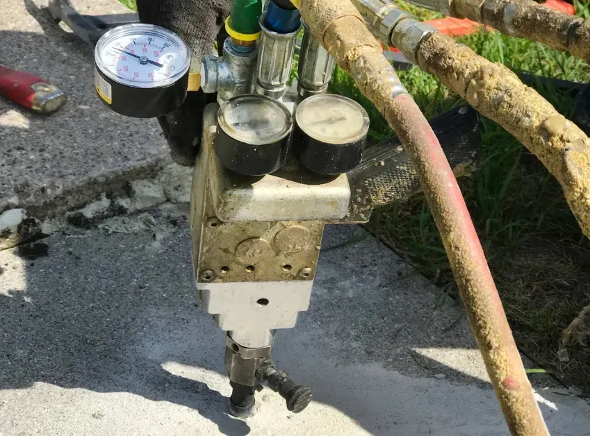 Water meter assembly with gauge and hoses on a concrete surface outdoors