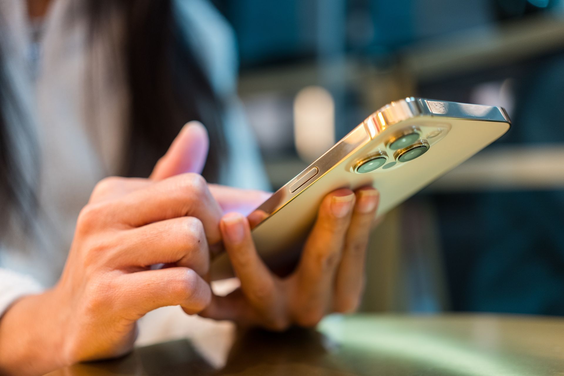 Hands holding a gold smartphone with a close-up view of the screen and case.