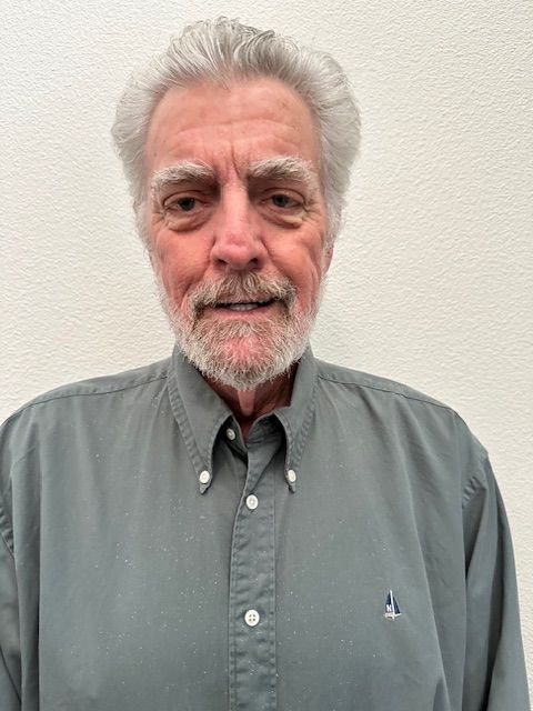 A woman wearing glasses and a blue shirt is smiling for the camera.