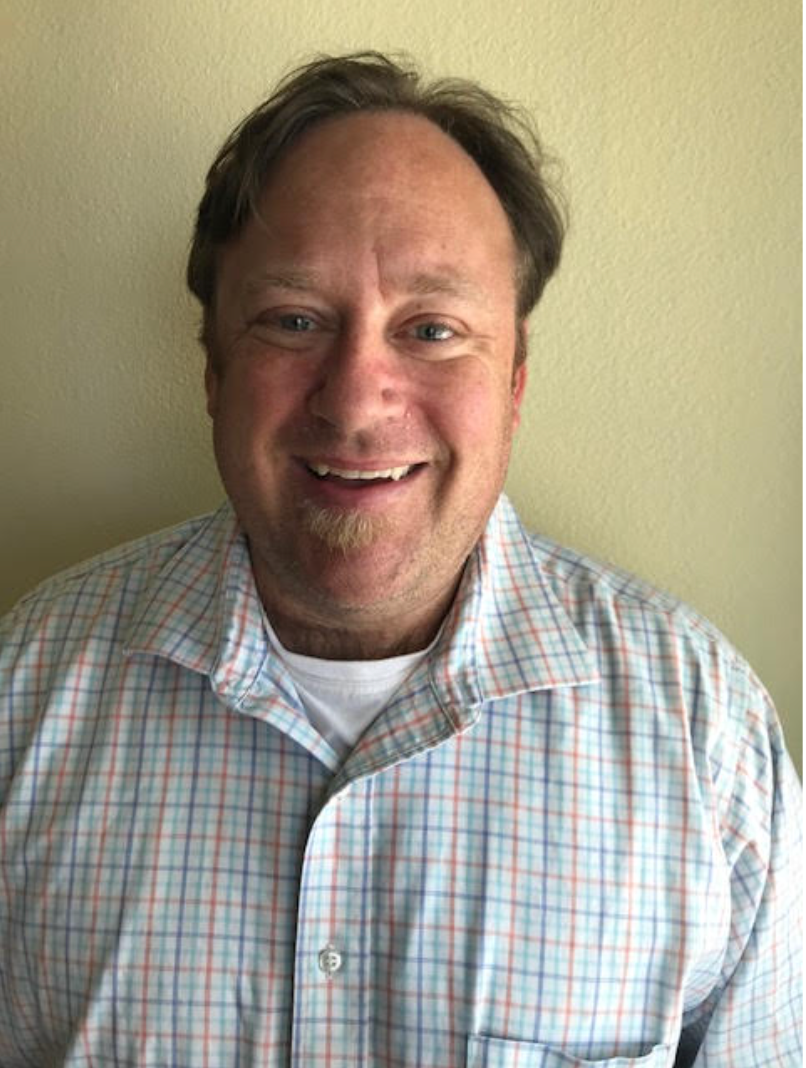 A man in a plaid shirt is smiling for the camera.