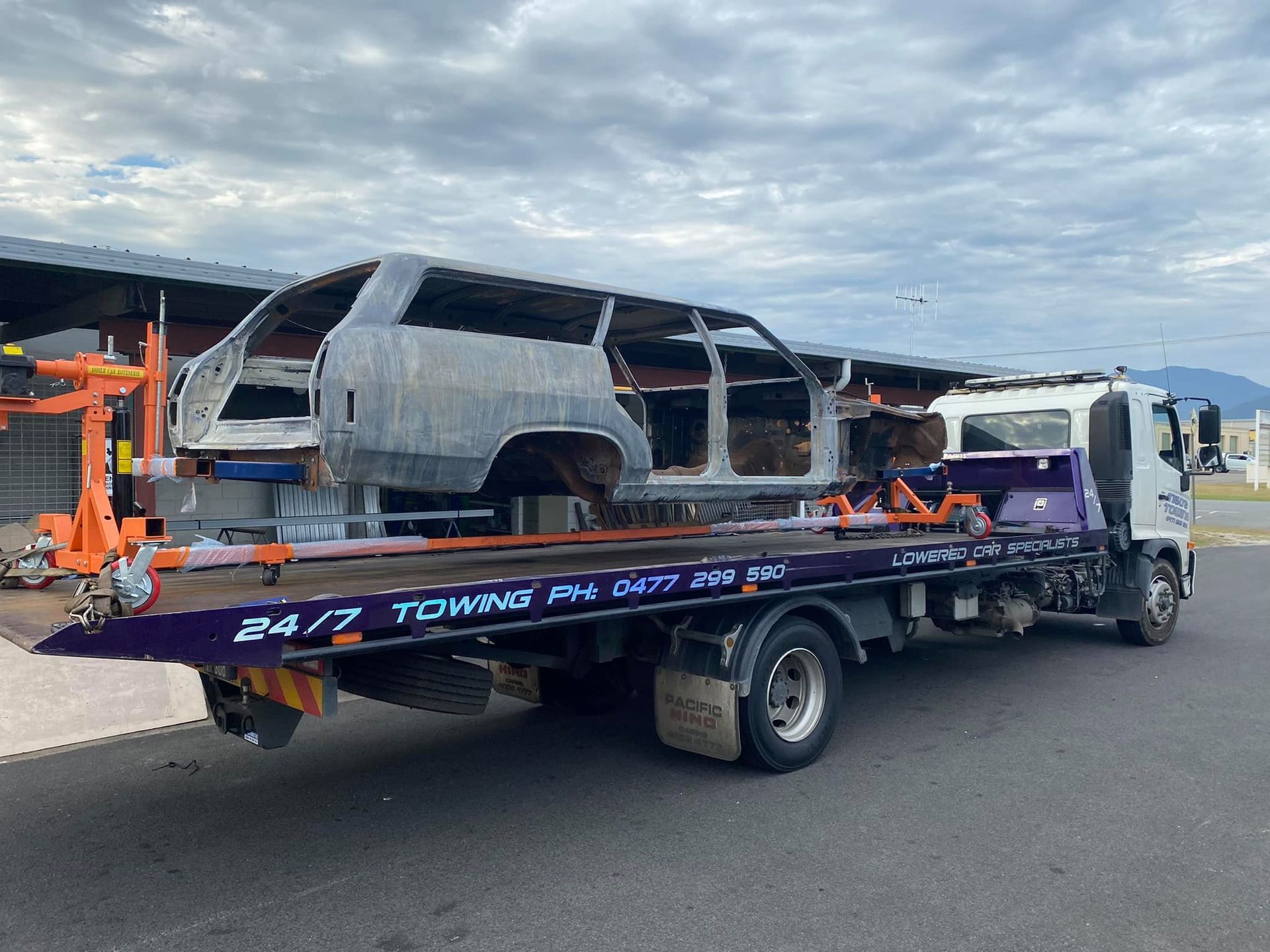 a Partially Built Car Body on a Tow Truck, Parked Under a Cloudy Sky — Tigo’s Towing In Cairns City, QLD
