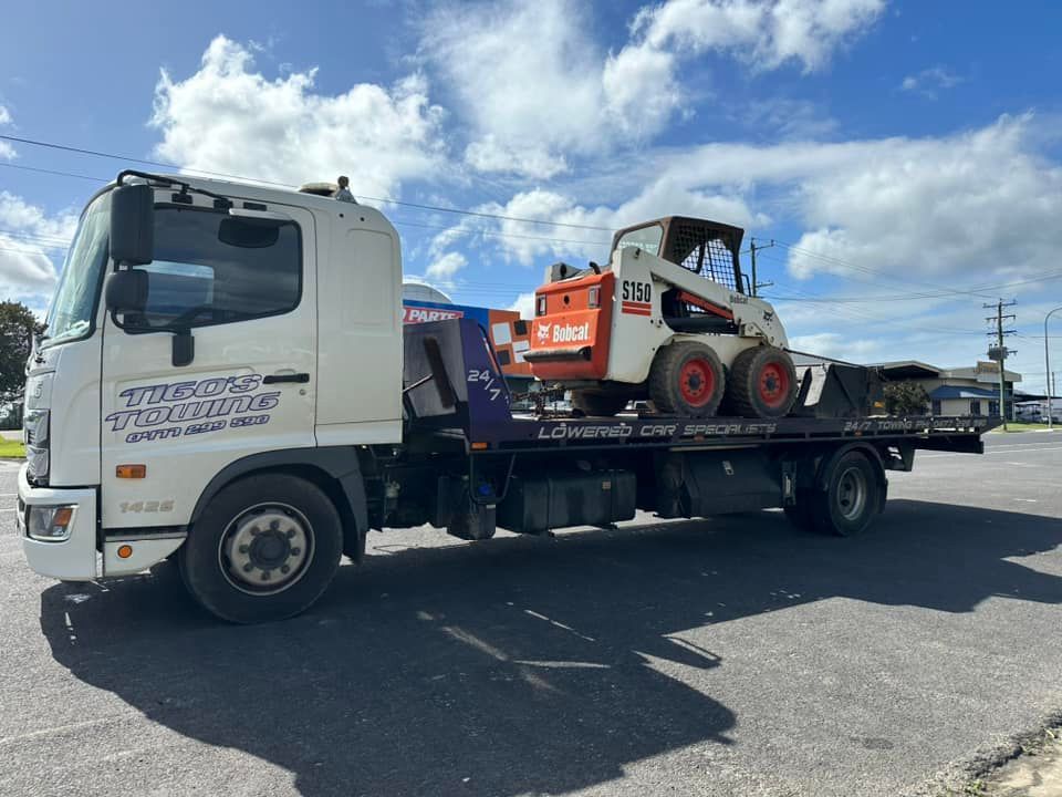 Tow Truck Hauling a Bobcat Skid-steer Loader on a Sunny Day — Tigo’s Towing In Cairns City, QLD