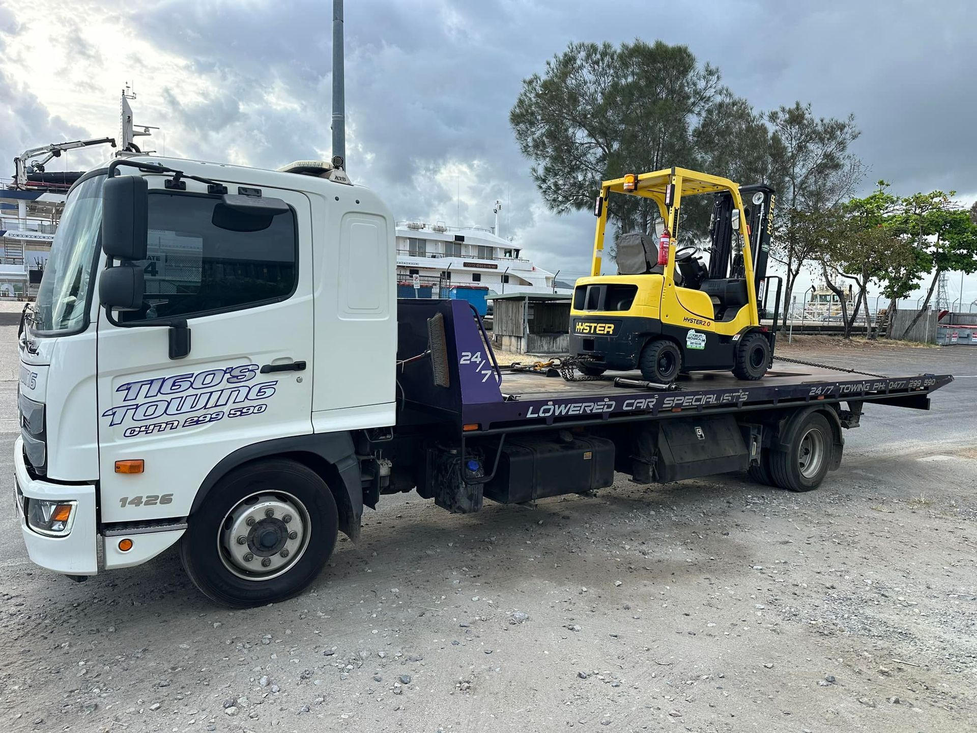 White Tow Truck Transporting a Yellow Forklift on Its Flatbed — Tigo’s Towing In Cairns City, QLD