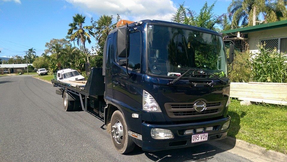 Dark Blue Flatbed Tow Truck on a Street, With a White Vehicle Loaded on Its Bed — Tigo’s Towing In Cairns City, QLD