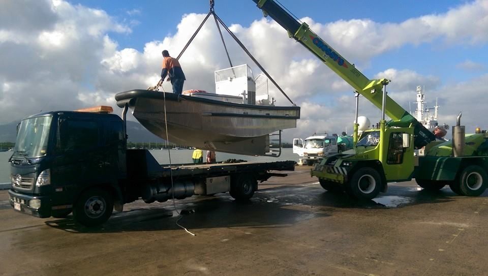 a Small Boat Being Lifted by a Crane — Tigo’s Towing In Cairns City, QLD