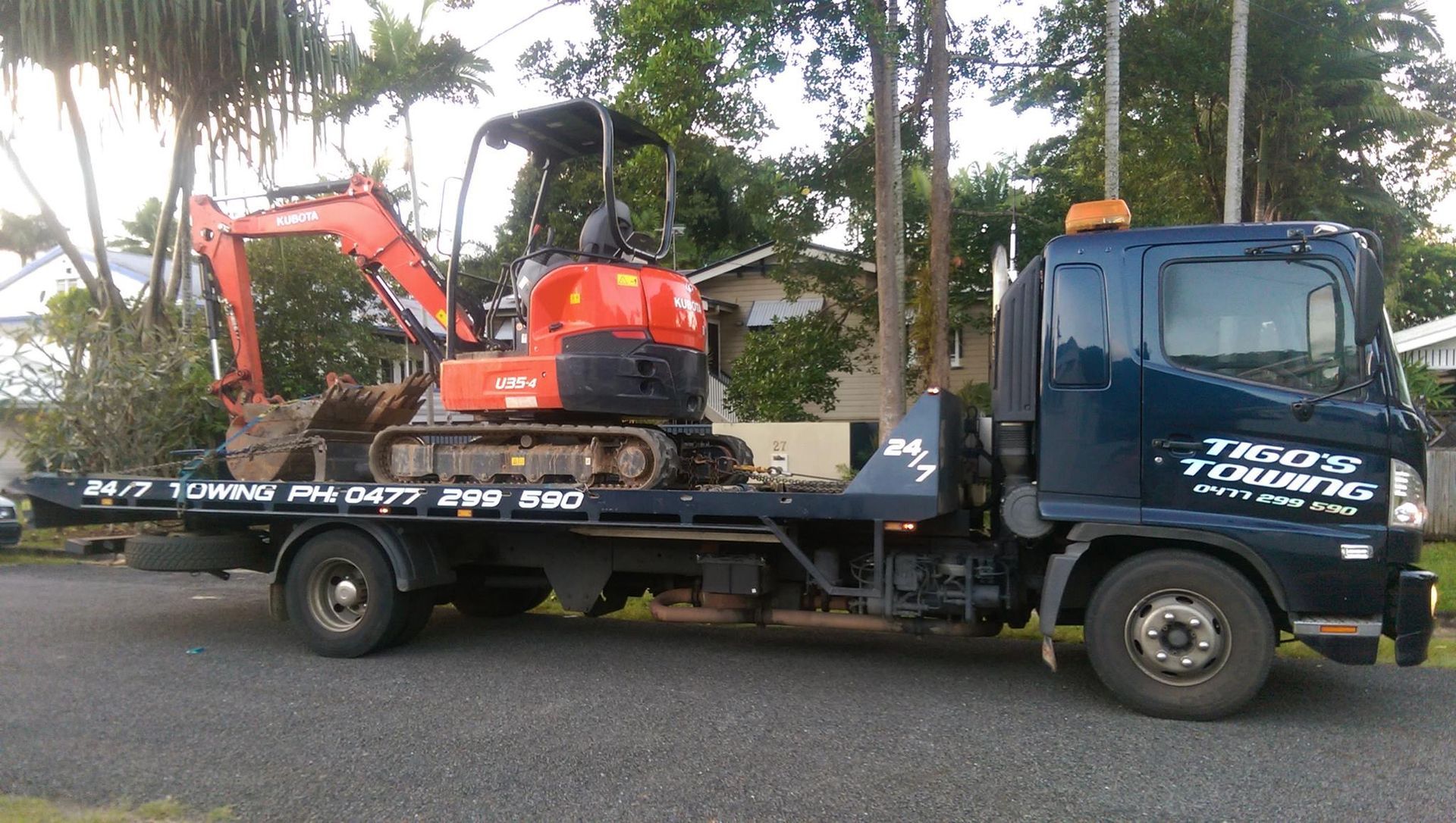 Flatbed Truck Carrying an Orange Kubota Excavator — Tigo’s Towing In Cairns City, QLD