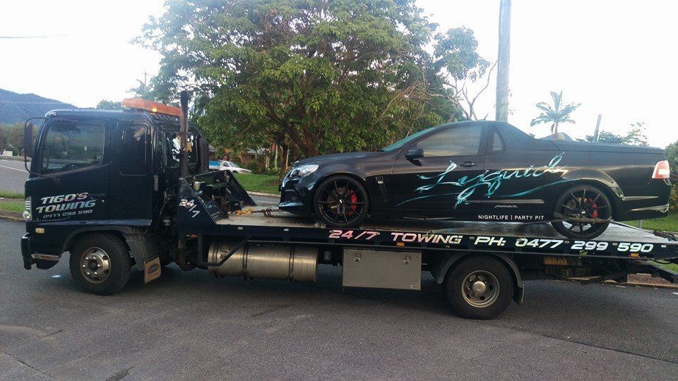 Black Tow Truck Carrying a Black Ute With Red Wheels — Tigo’s Towing In Cairns City, QLD
