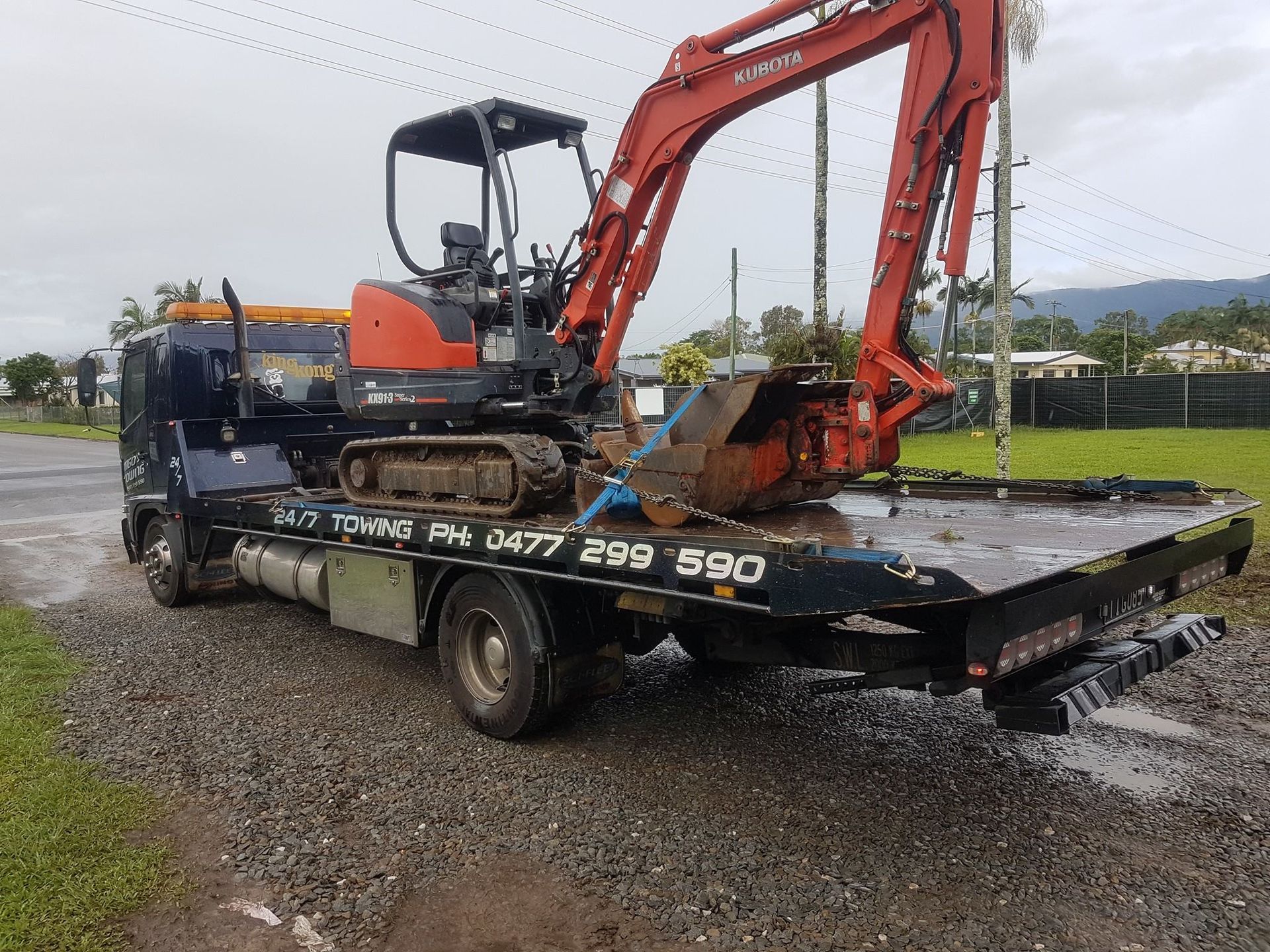 Mini Excavator Loaded on a Tow Truck, Parked on a Gravel Road — Tigo’s Towing In Cairns City, QLD
