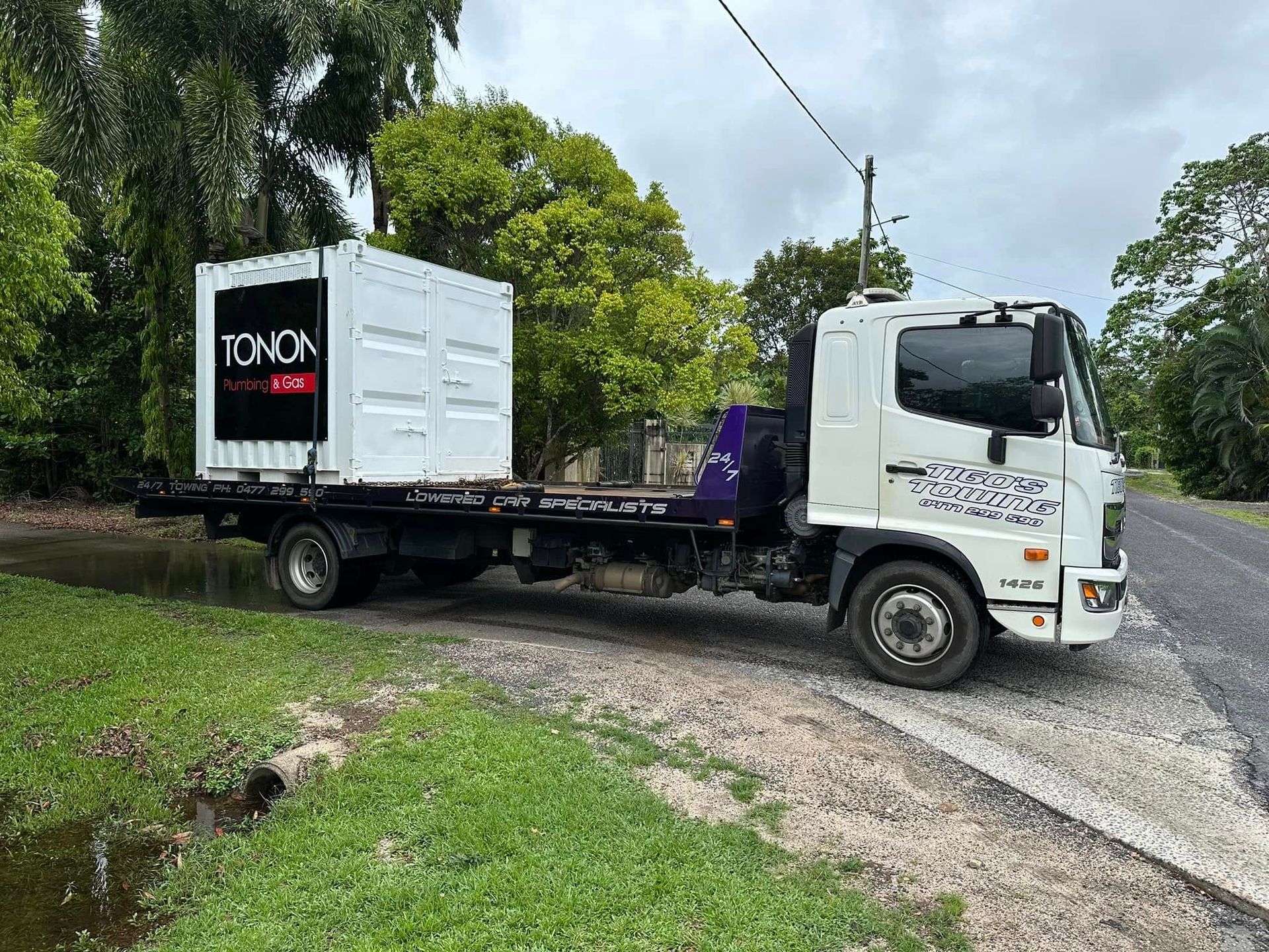 A White Truck Hauling a White Storage Container on a Flatbed Trailer — Tigo’s Towing In Cairns City, QLD