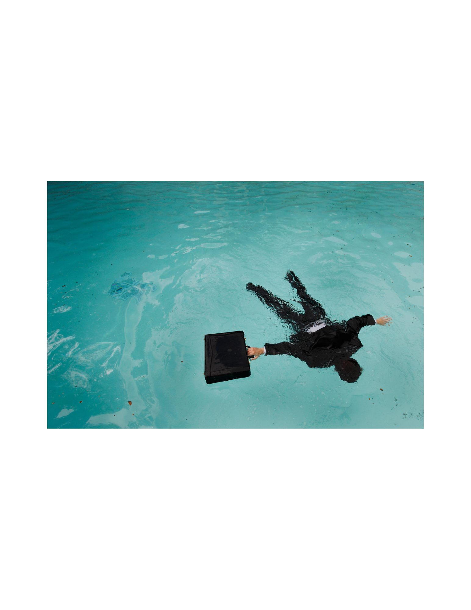 Man in suit floating in pool, holding briefcase.