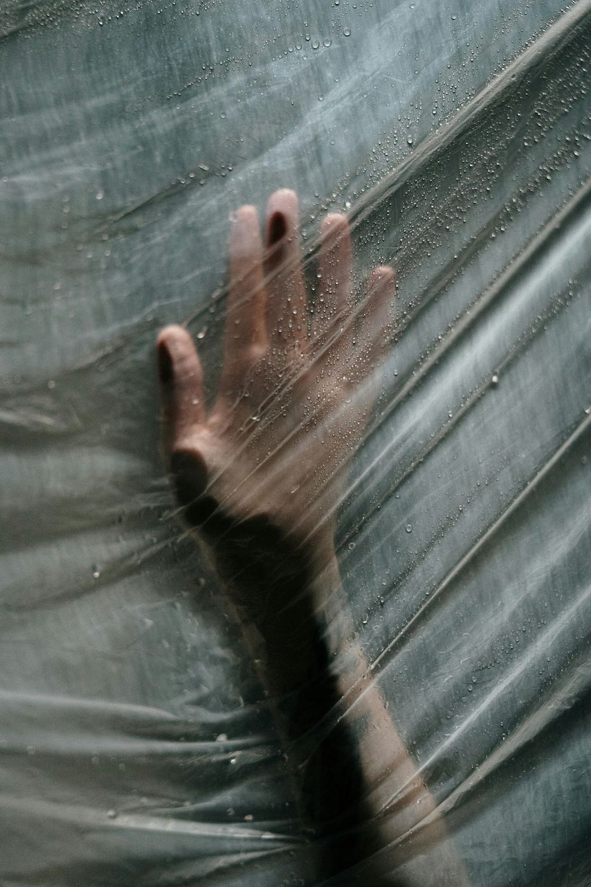 A person 's hand is sticking out of a plastic bag.